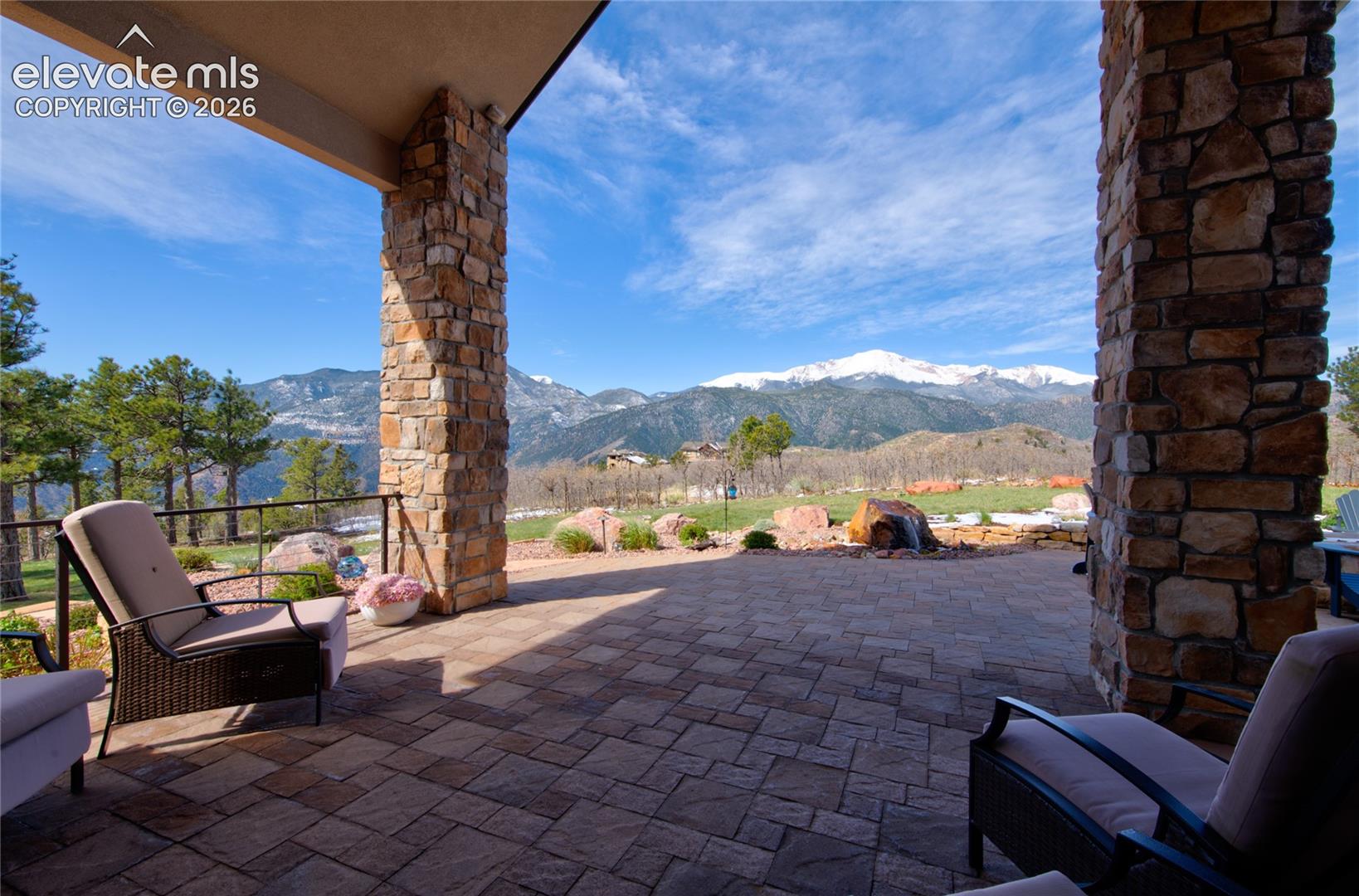 The best seat in Colorado Springs. Covered main-level patio with paver flooring, integrated speakers, glass railing, and uninterrupted views of Pikes Peak and the valley below.
