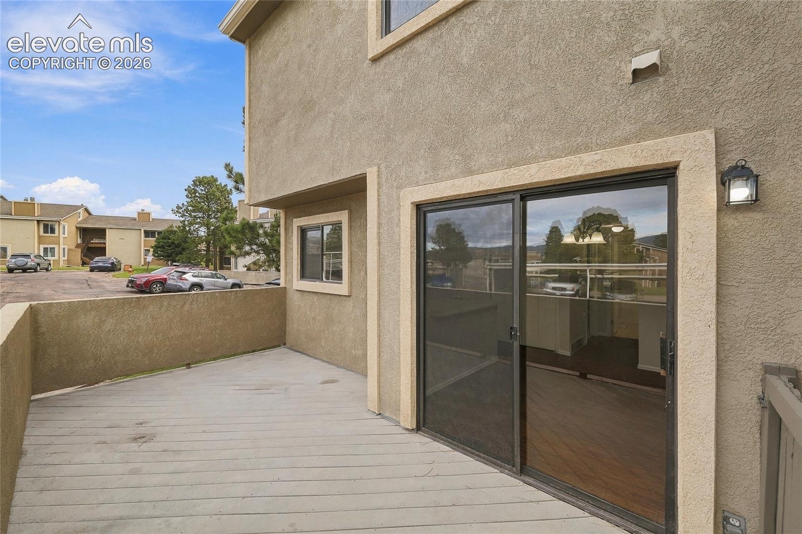 Exterior deck featuring a stucco-finish privacy wall and sliding glass door access