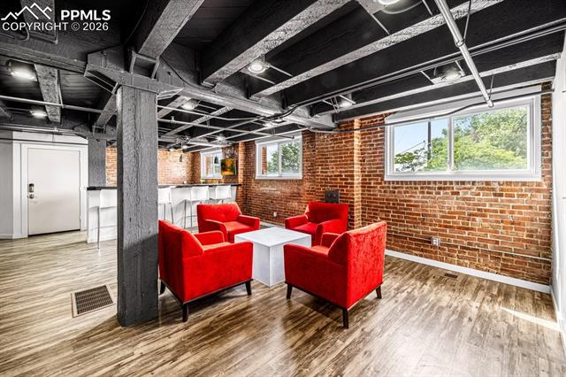 featuring brick wall and wood finished floors