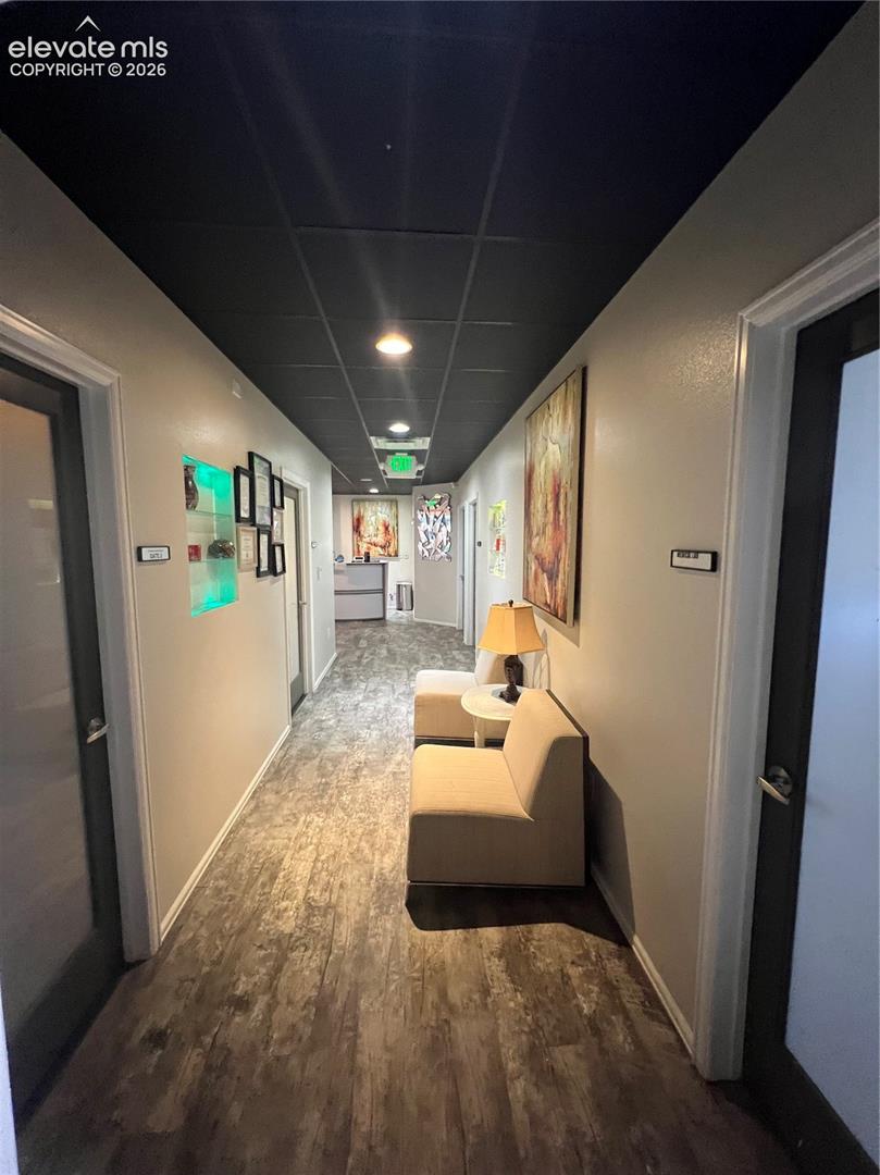 Hallway featuring wood-finish flooring, a suspended black acoustic tile ceiling, recessed lighting, and a recessed wall niche with integrated accent lighting