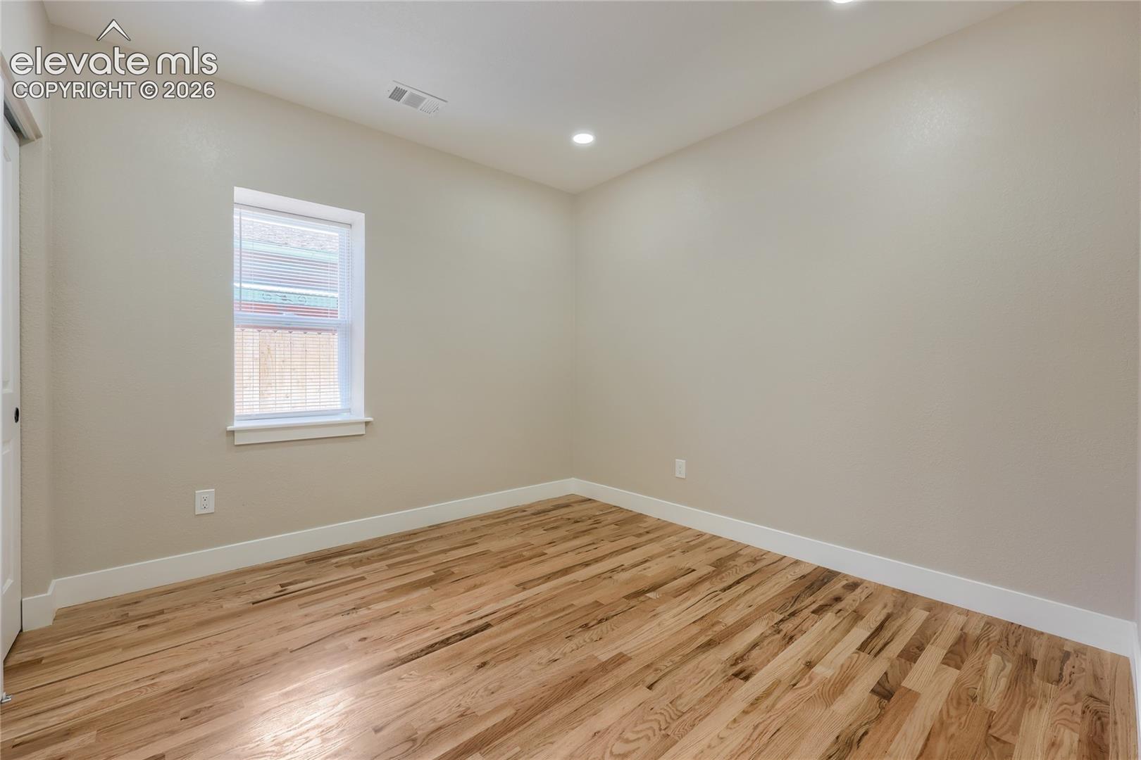 A well-sized second bedroom is comfortable, featuring soft natural light, hardwood flooring, and a double-slider door to a spacious reach-in closet. This room offers easy access to the main hall bath.