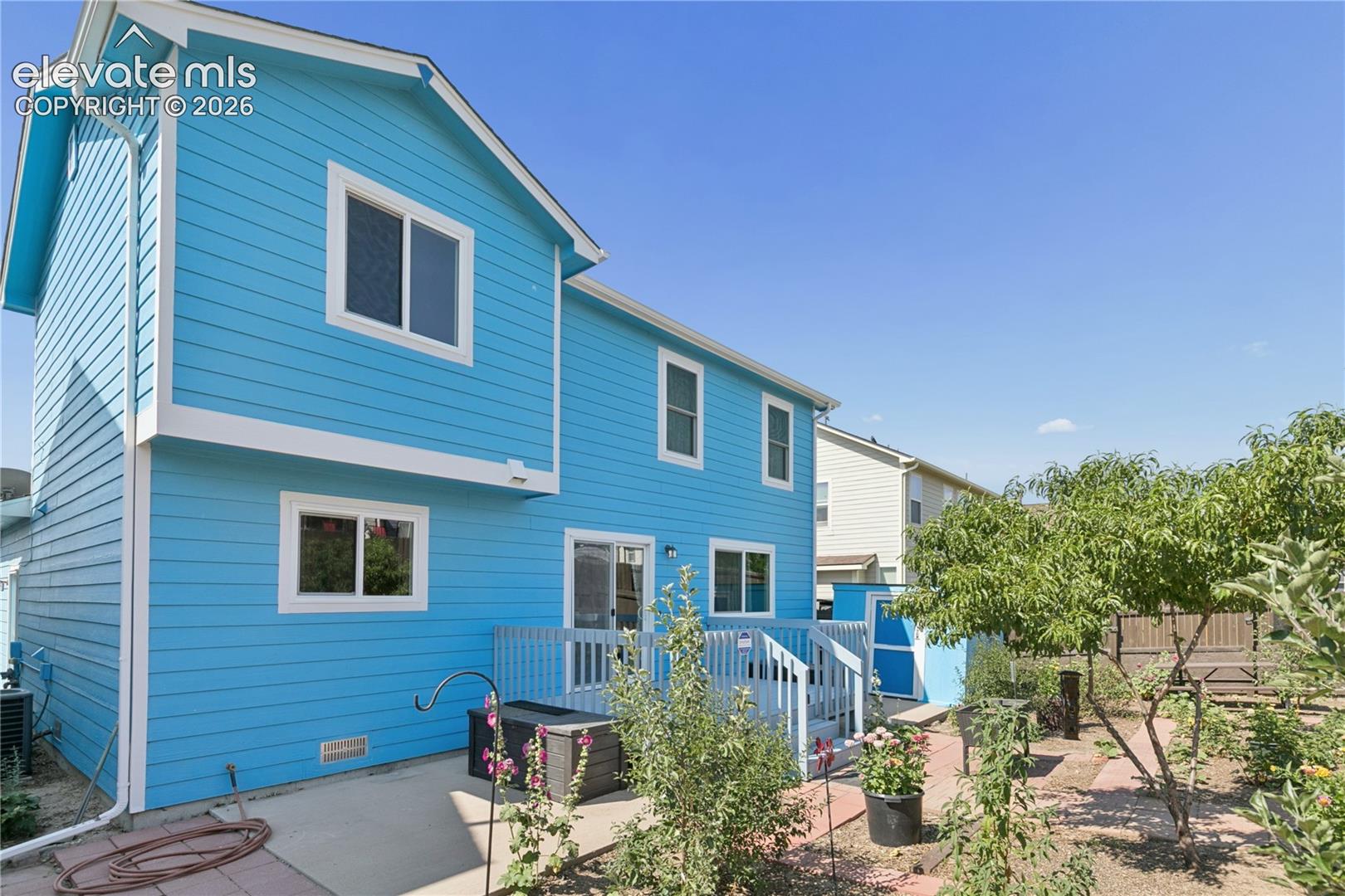 Exterior with vibrant blue siding, white trim, and a multi-level deck