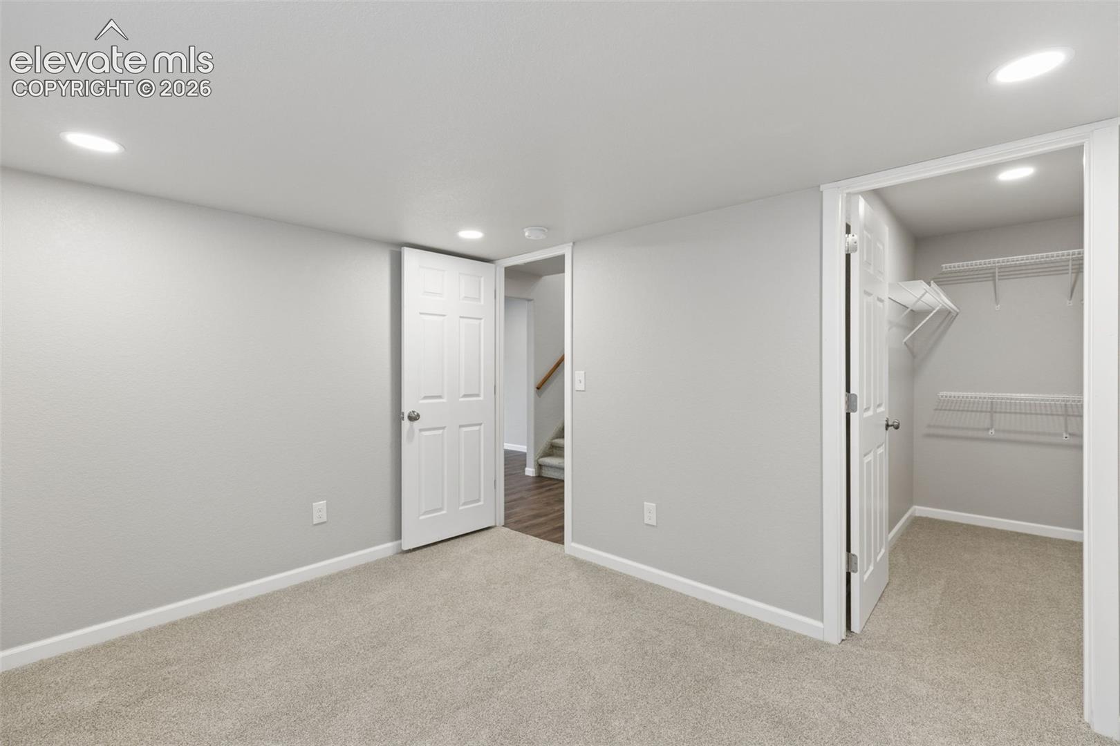 Neutral-toned interior space featuring recessed ceiling lighting, wall-to-wall carpeting, and a walk-in closet with built-in wire shelving