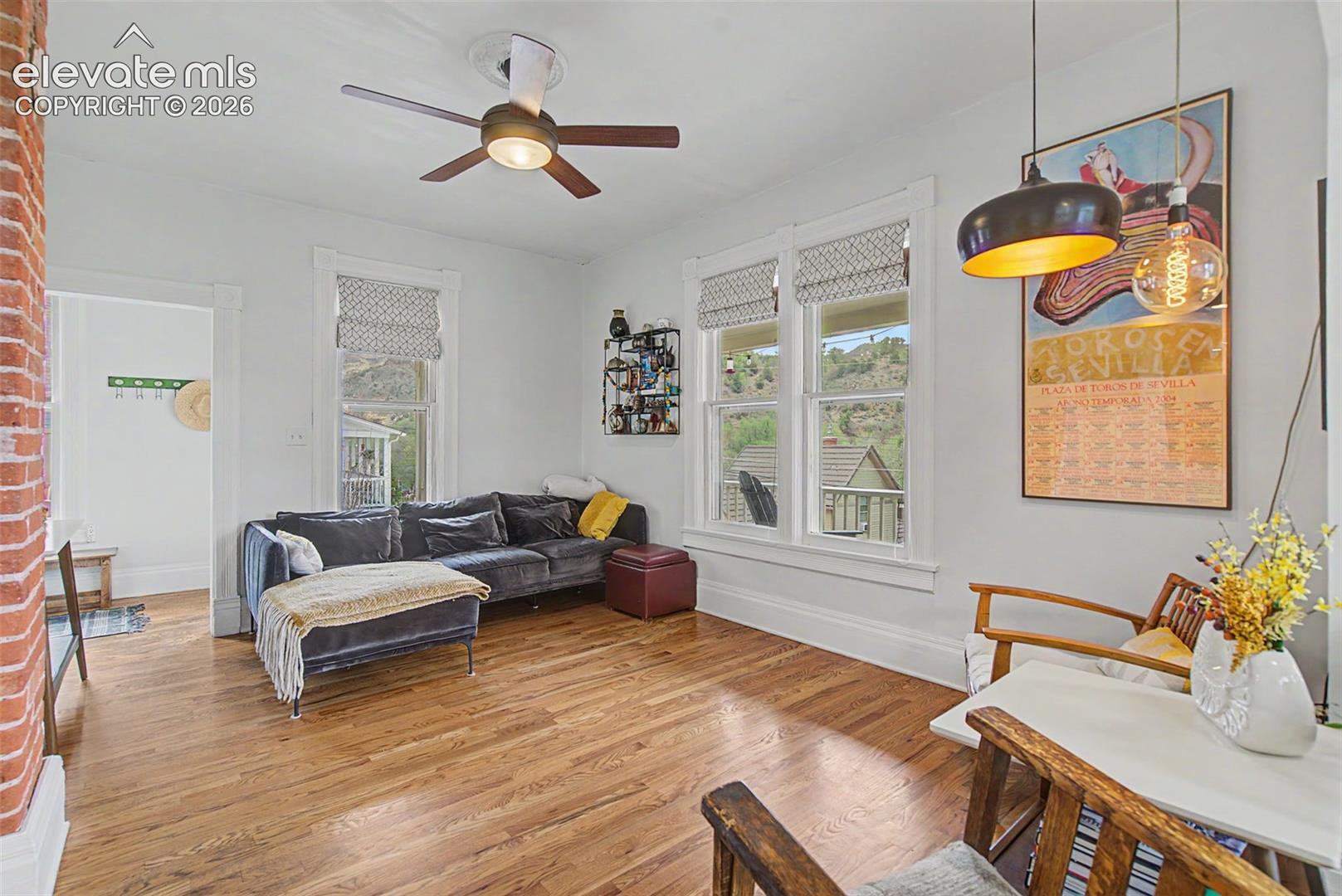 Living area featuring hardwood flooring, exposed brick, and natural lighting