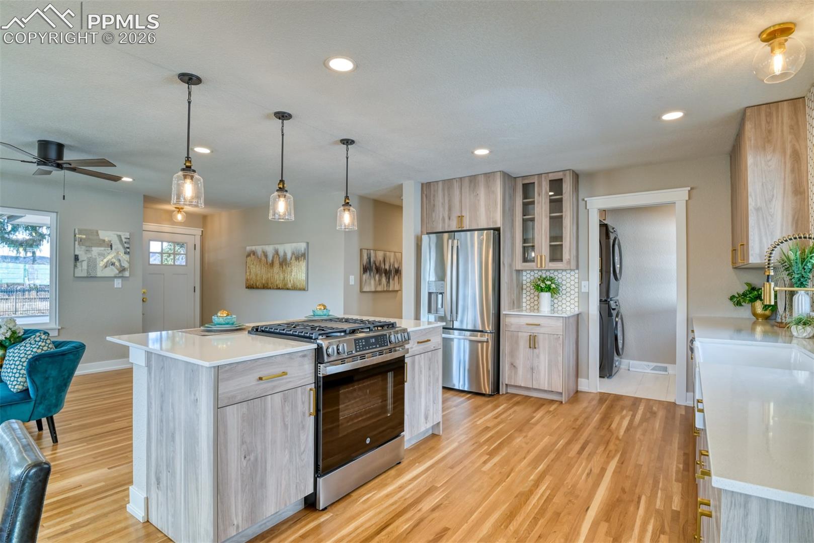 Kitchen with stainless steel appliances, pendant lighting, ceiling fan, light stone countertops, and dual tone cabinets