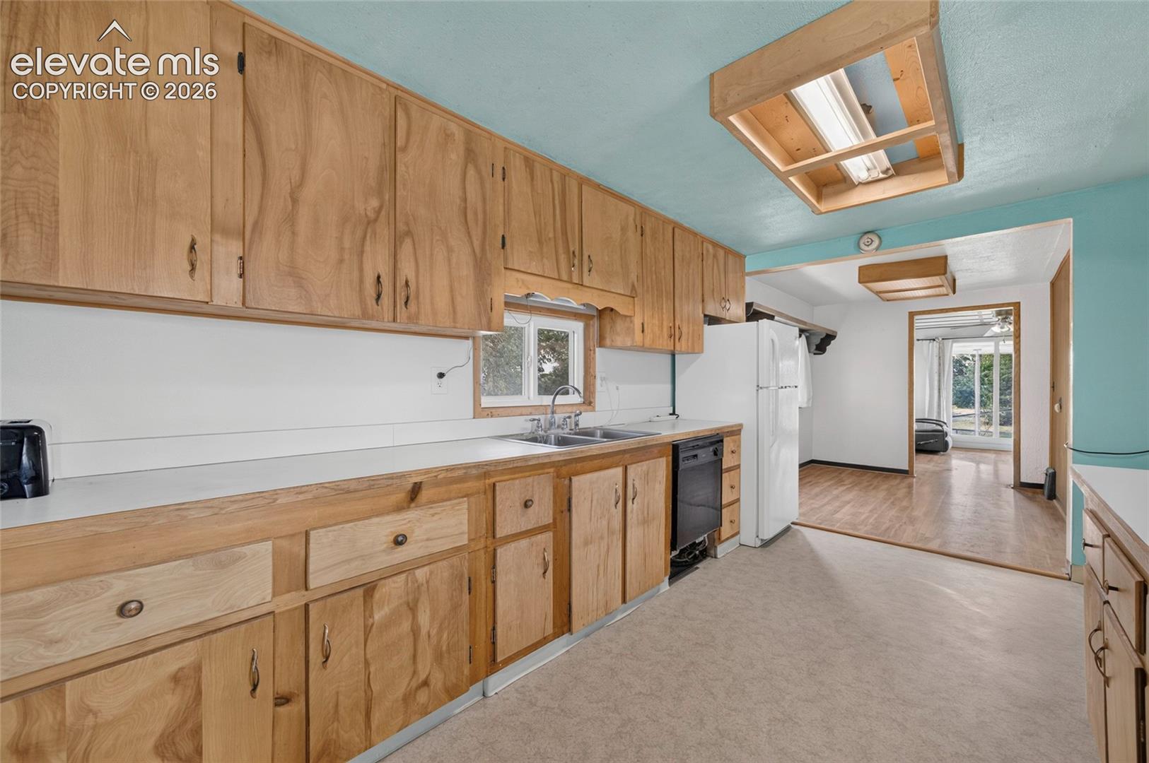 Wood cabinetry throughout, built-in dishwasher, and a double basin sink