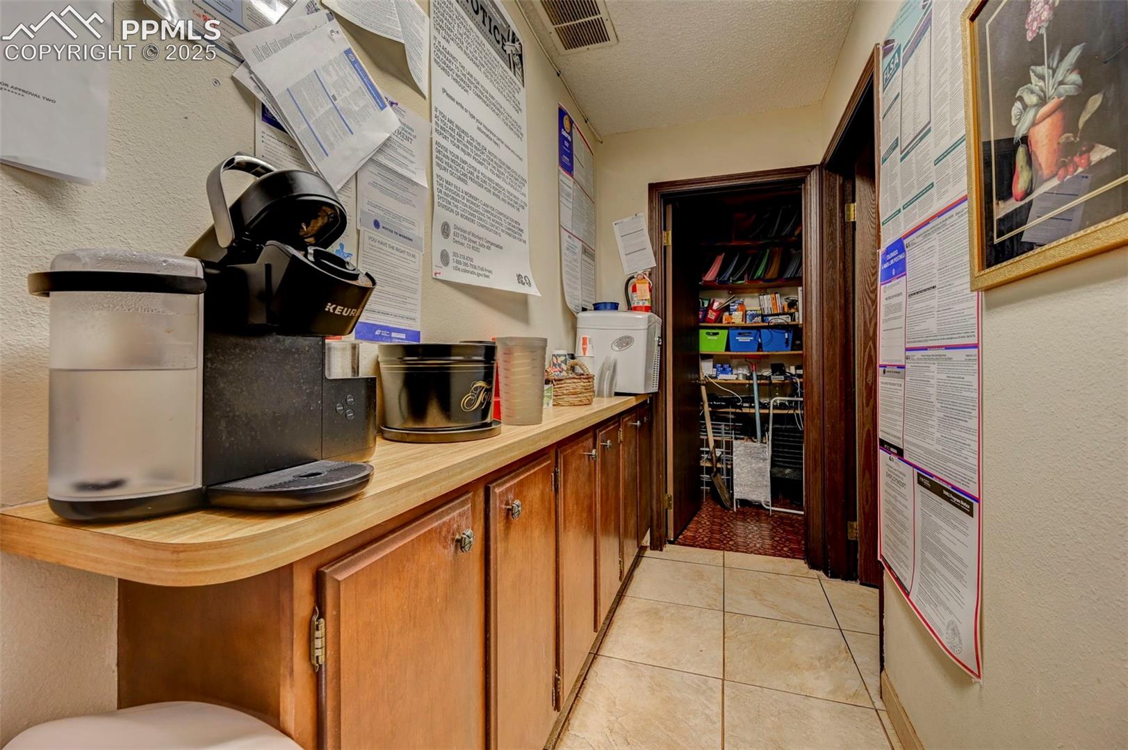 Kitchen featuring light countertops, brown cabinets, a textured ceiling, and light tile patterned floors