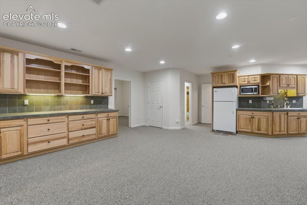 Recessed lighting illuminates extensive wood cabinetry with shelving and a built-in microwave