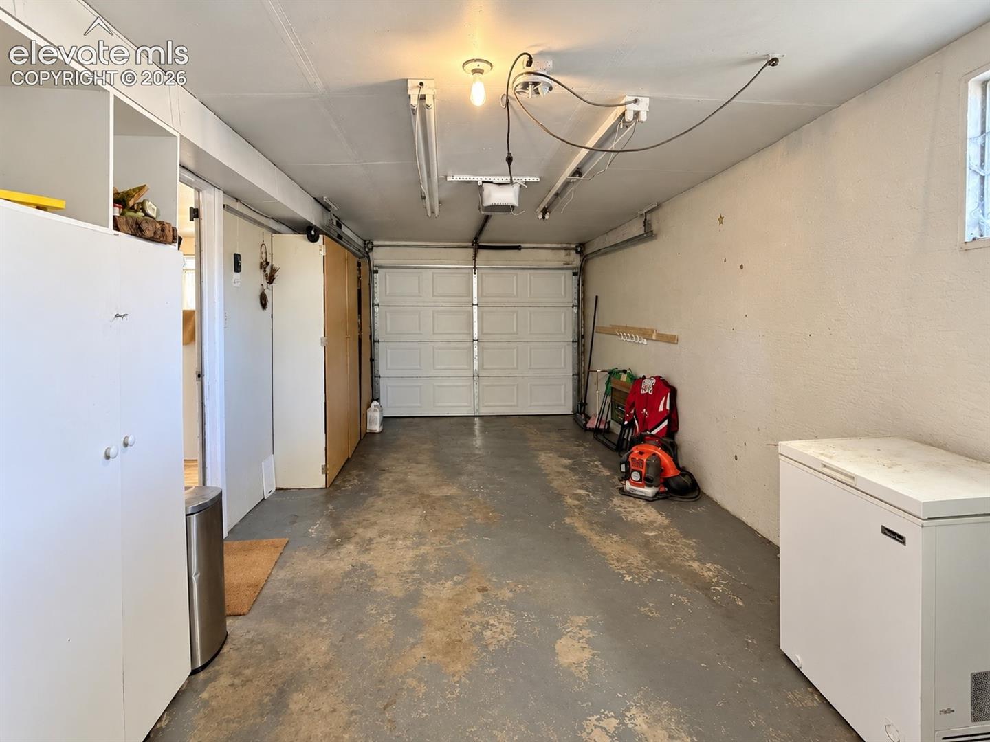Concrete flooring with textured walls, equipped with built-in storage cabinetry and overhead lighting fixtures