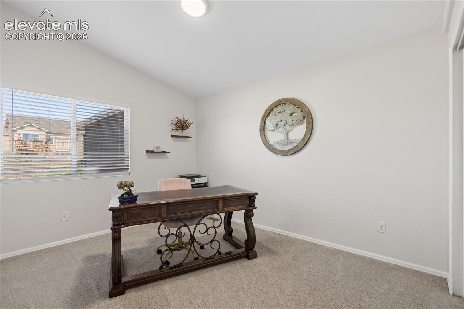 Vaulted ceiling, window with horizontal blinds, and carpeted flooring
