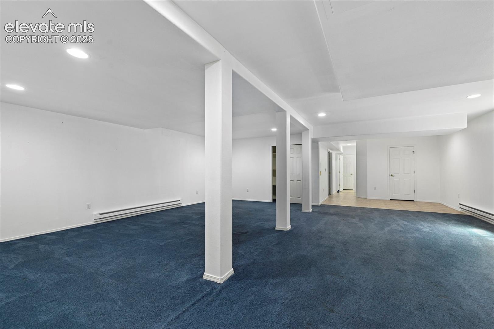 Expansive room featuring blue carpeting, recessed lighting, white walls, and multiple entry points
