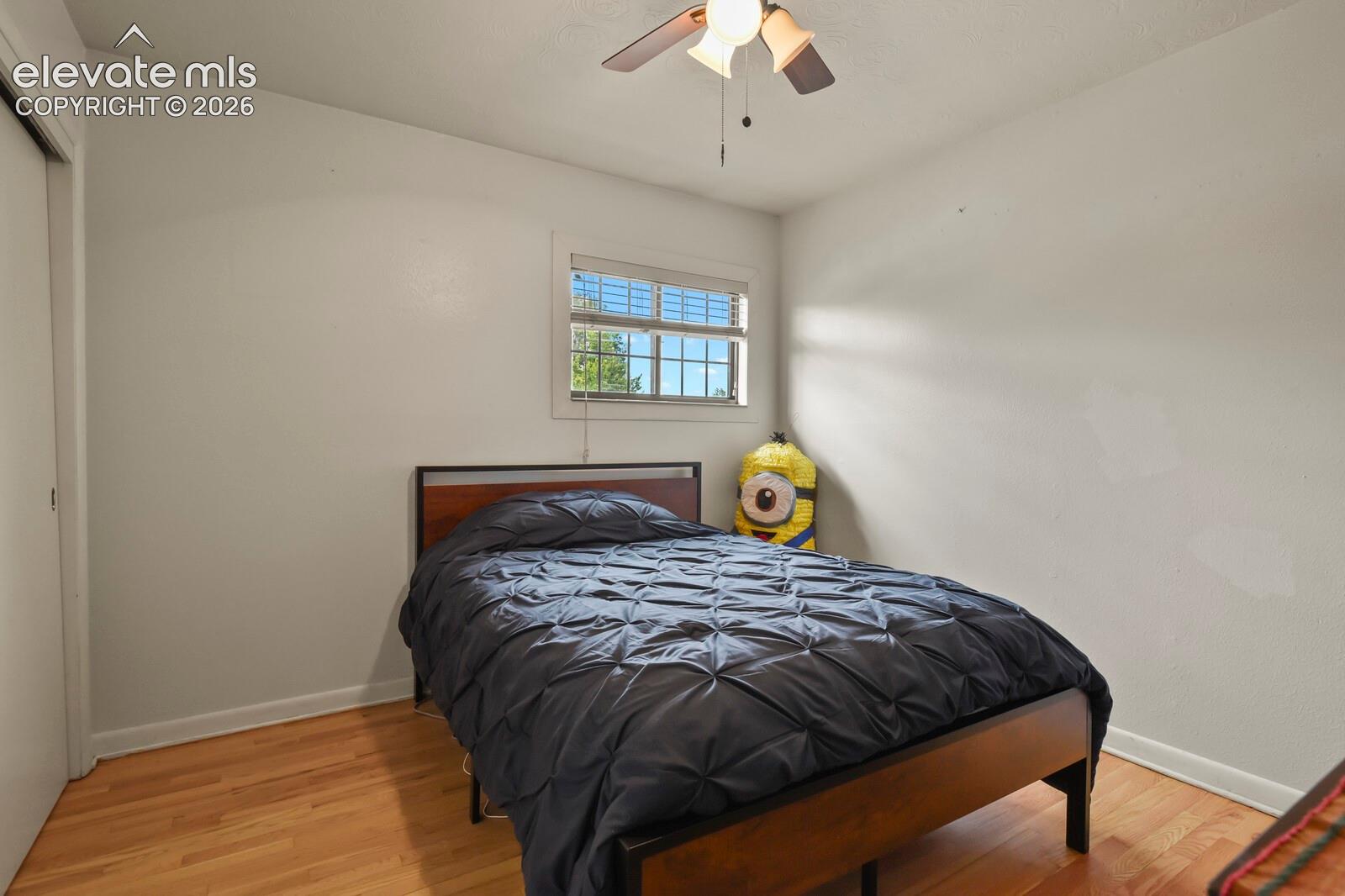 Hardwood flooring, window with blinds, ceiling fan with integrated lighting, and a closet with sliding doors