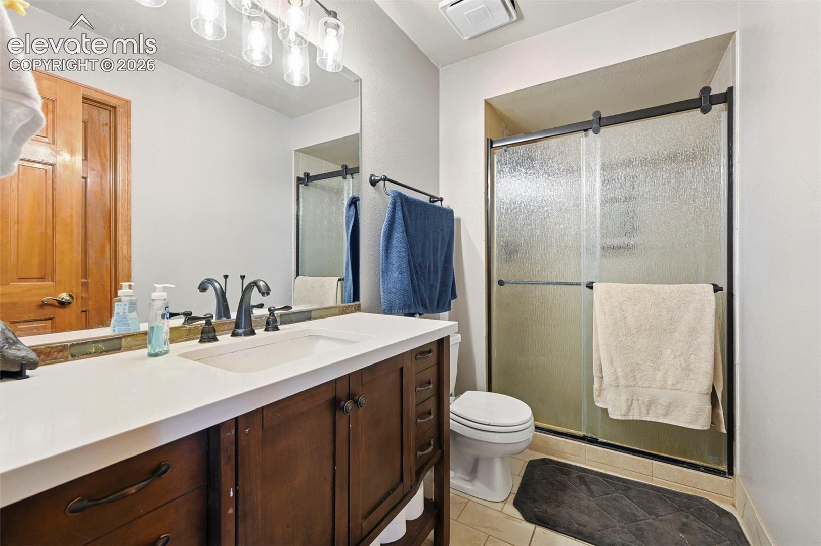 Main level bathroom with wood-finish vanity and white countertop, undermount sink, and dark bronze fixtures