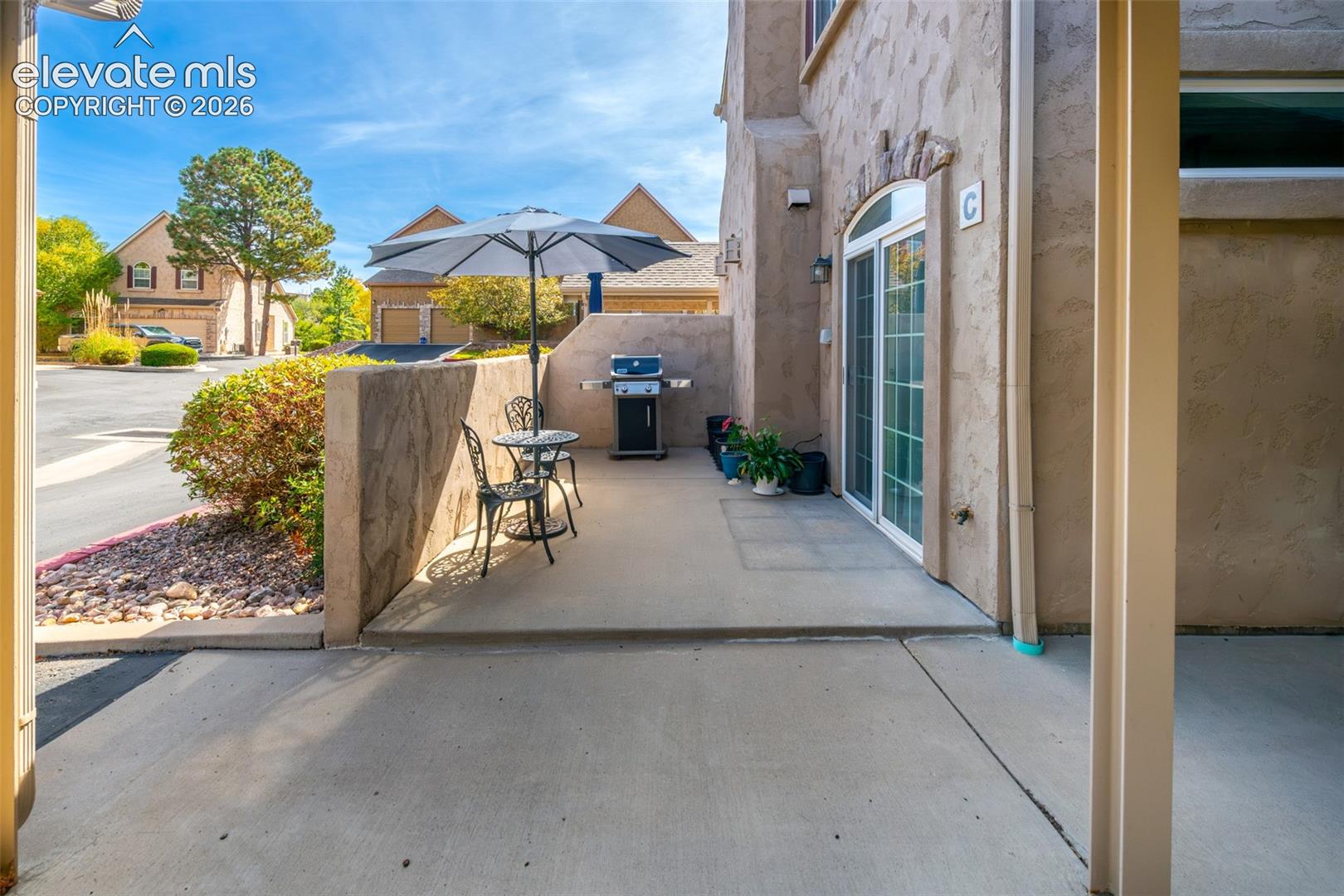 Concrete patio with an arched glass sliding door, stone accent wall, and stucco exterior