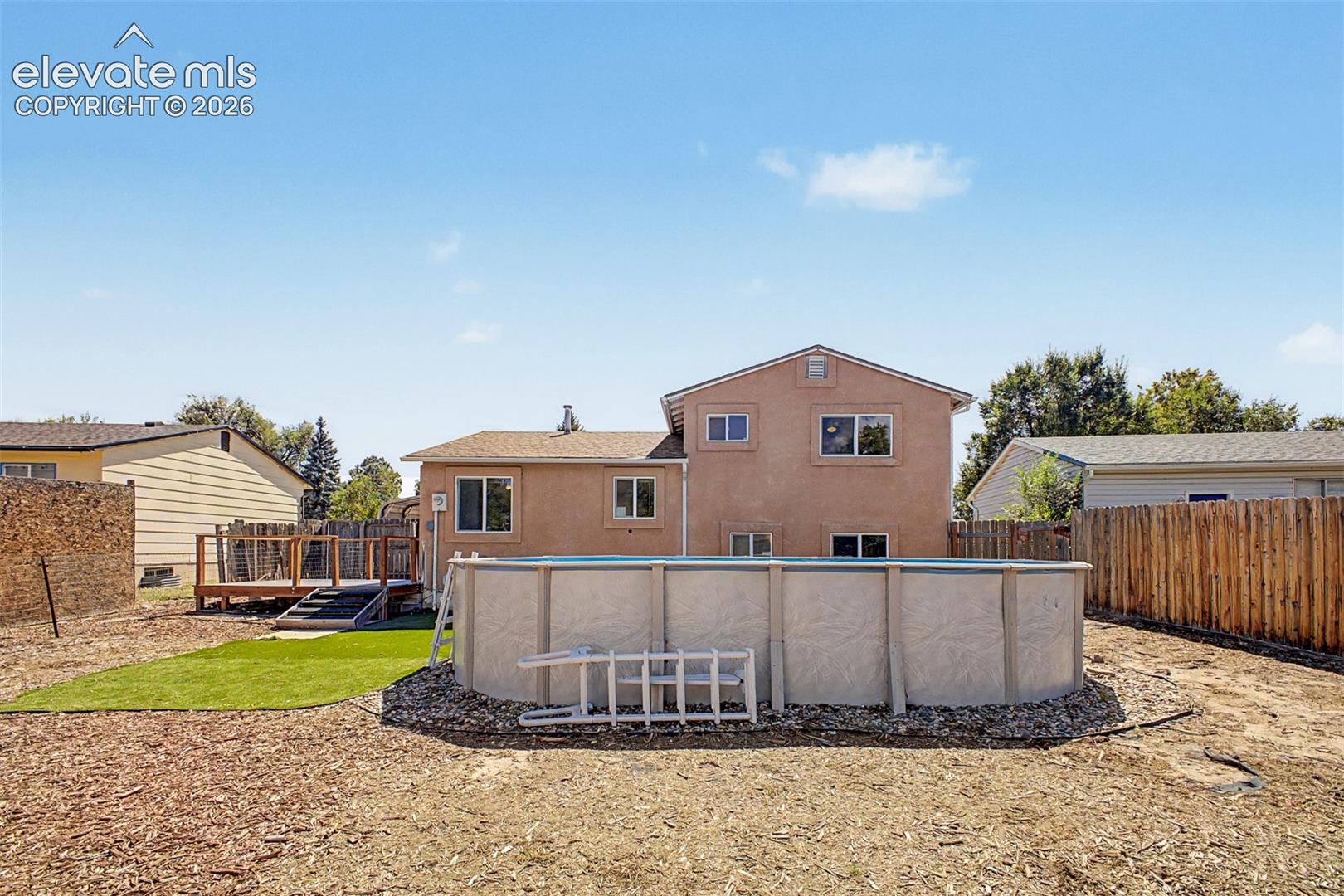 Expansive backyard featuring a deck with stairs, an above-ground pool (will be removed unless otherwise requested), and a partial artificial turf area