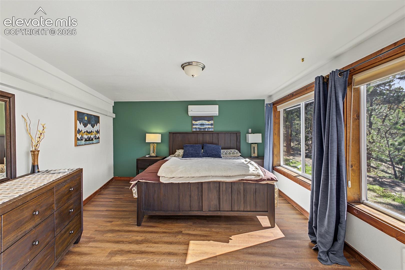 Wood-finish flooring, accent wall, air conditioning unit, recessed lighting, and large windows with natural wood frames