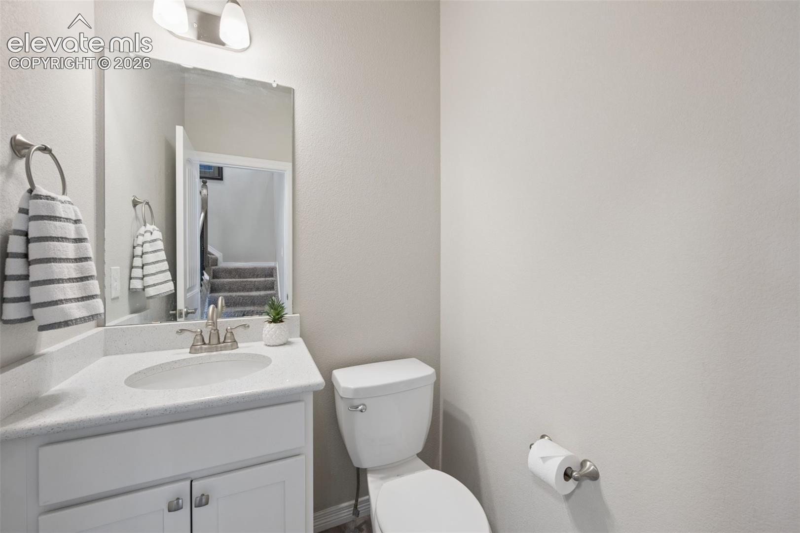 White vanity with a single basin sink, brushed nickel faucet, and a large wall-mounted mirror
