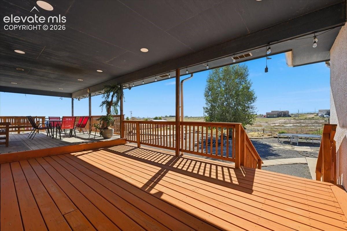 Covered patio featuring a wood-plank deck, recessed ceiling lighting, and a wood railing