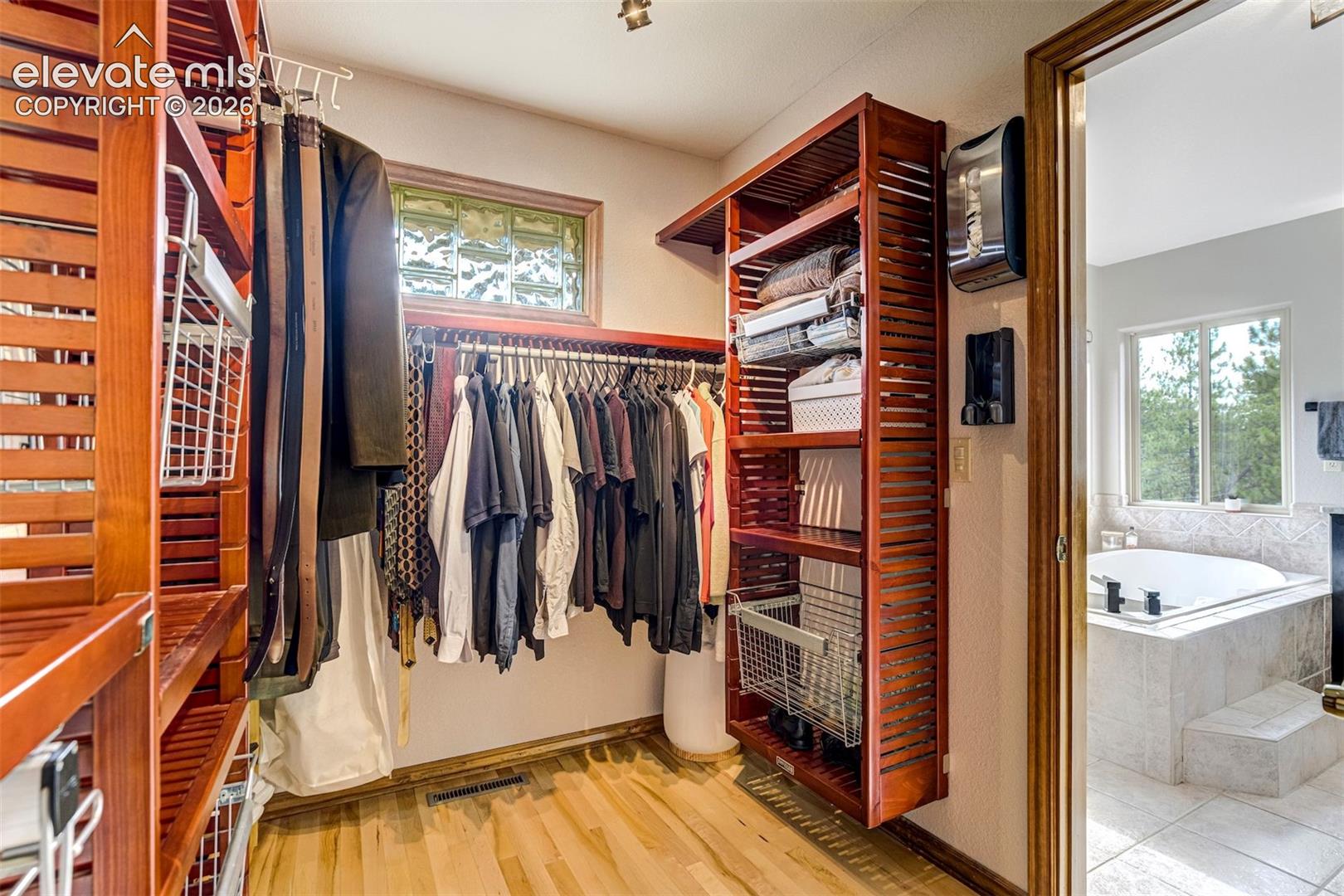 Custom closet organization system with wood-finish shelving and hanging rods