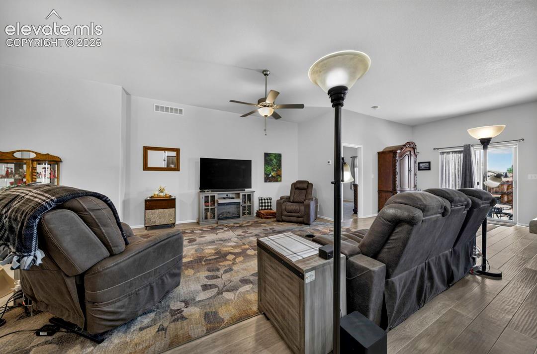 Spacious living area featuring wood-finish flooring and a central ceiling fan