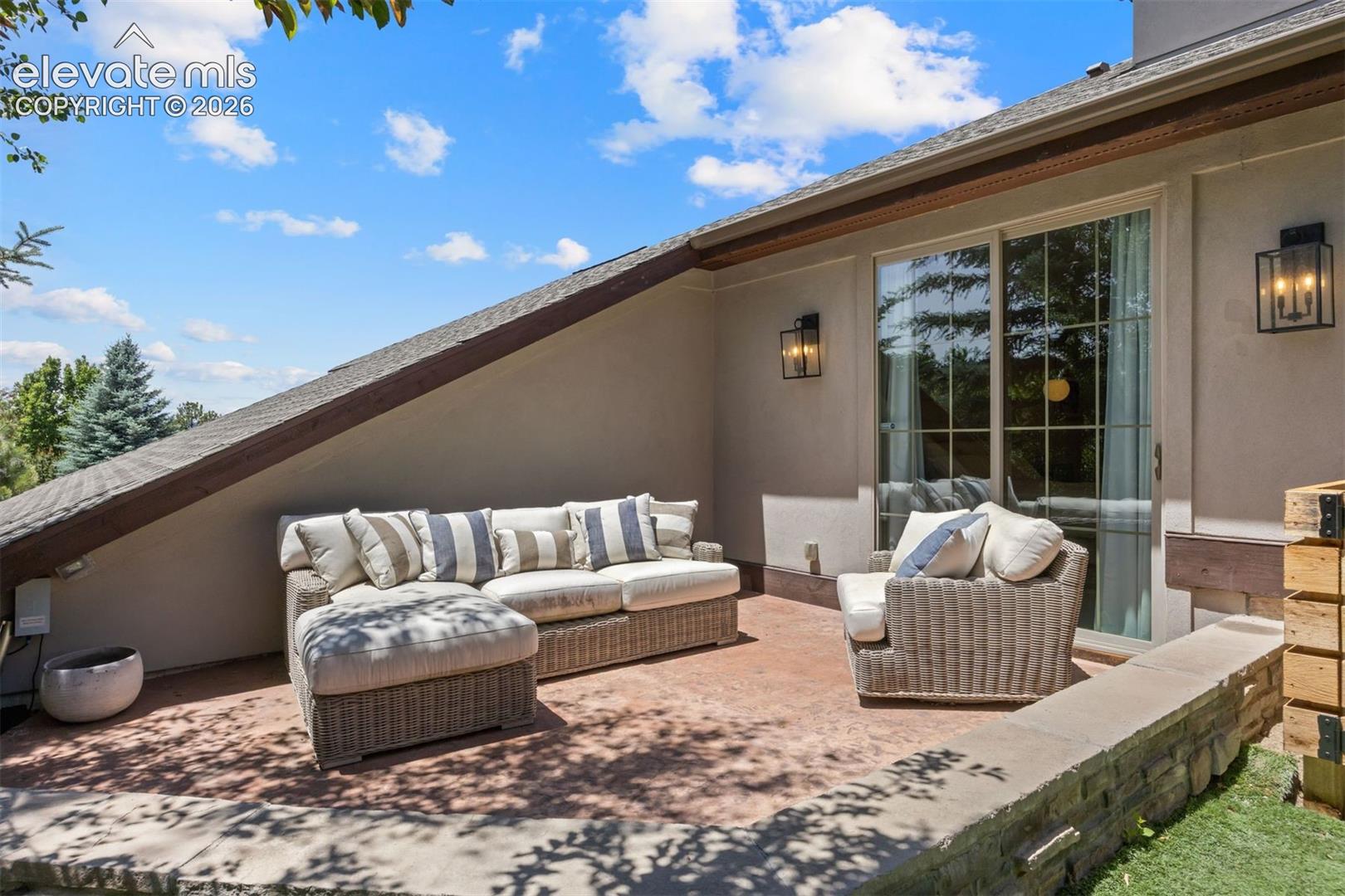 Patio area featuring a stucco exterior, exposed timber beam, and sliding glass doors