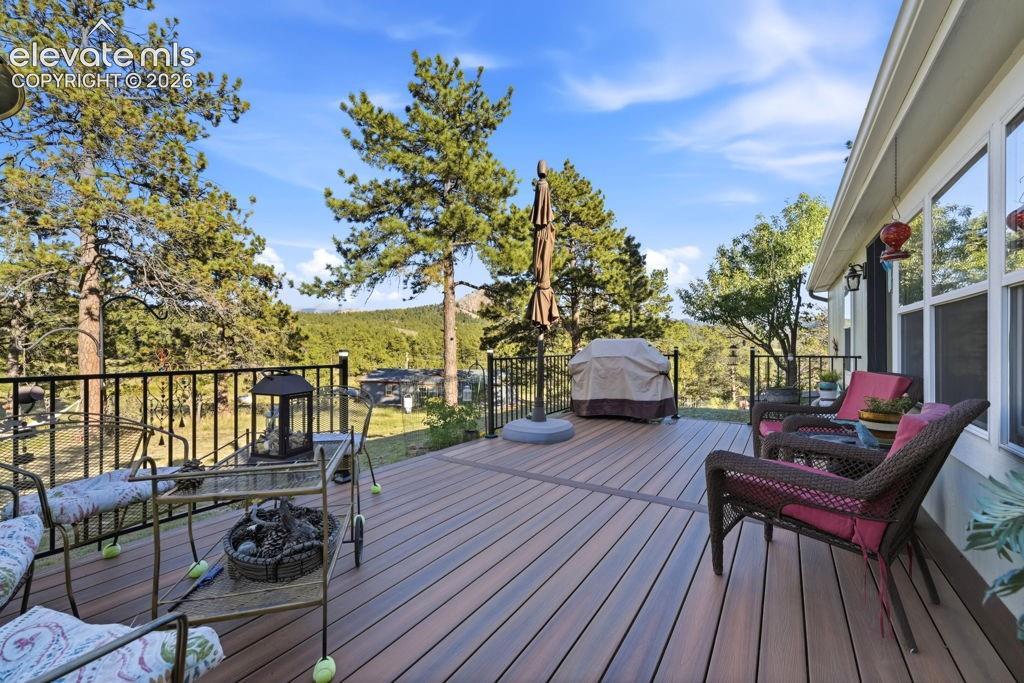 Expansive outdoor deck featuring wood-finish composite decking, black metal railing, and large windows