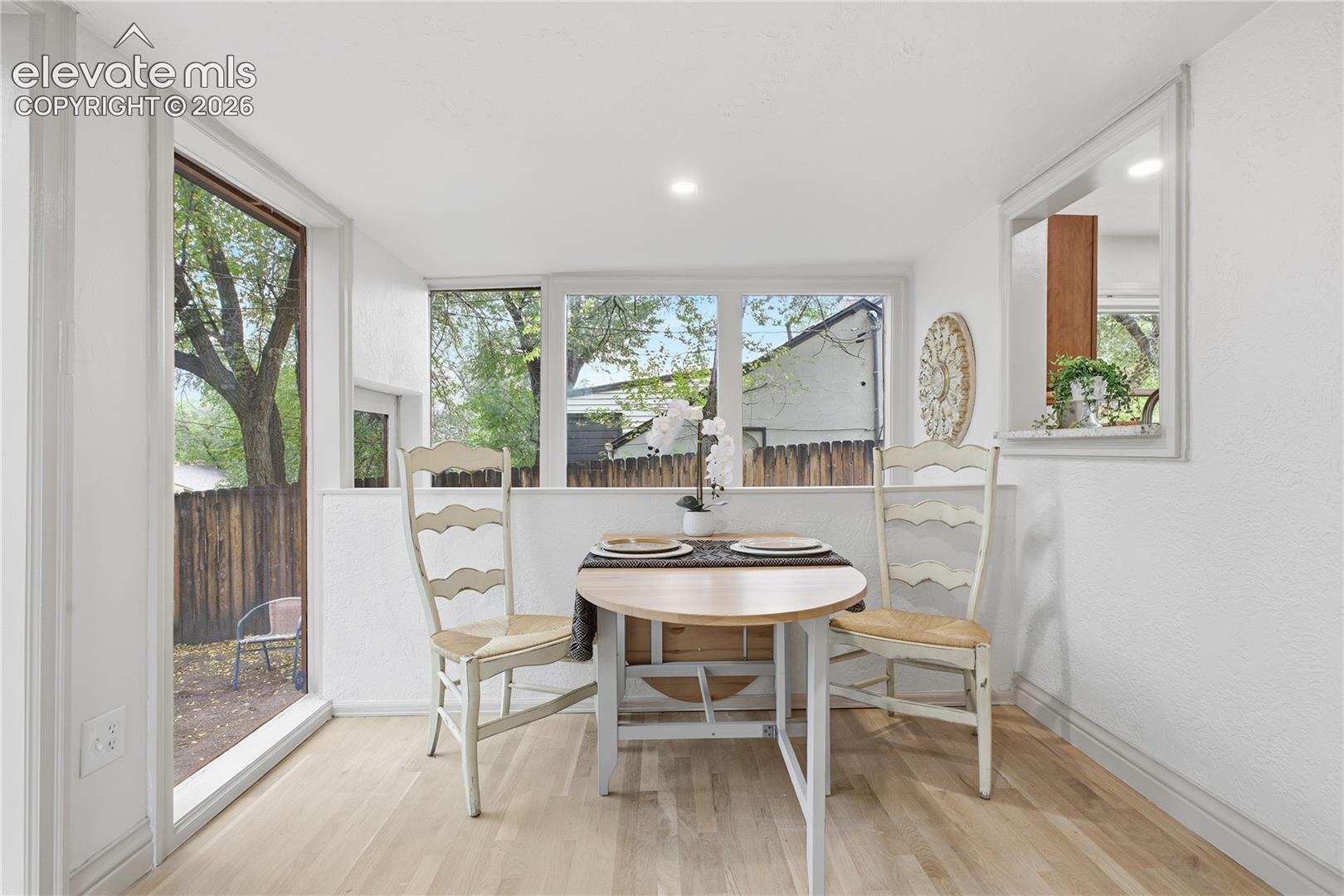 Sunroom featuring large windows, wood-finish flooring, and a pass-through window opening