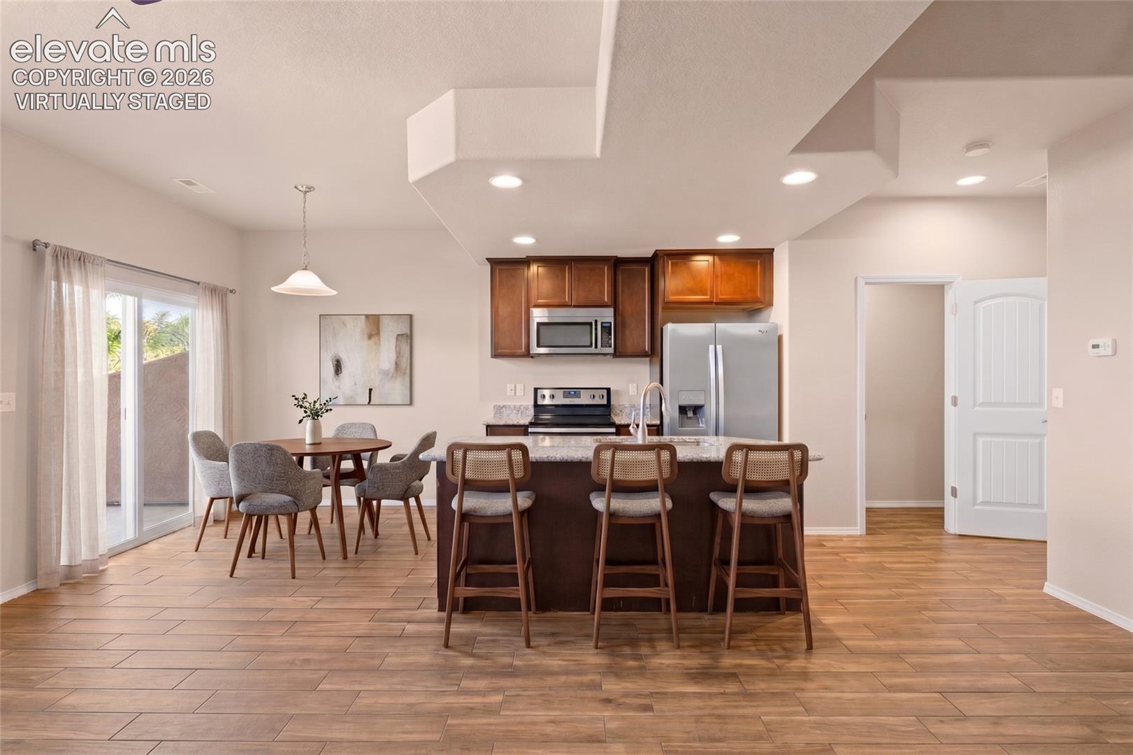 Wood-finish flooring, recessed lighting, and a kitchen island with seating - virtually staged