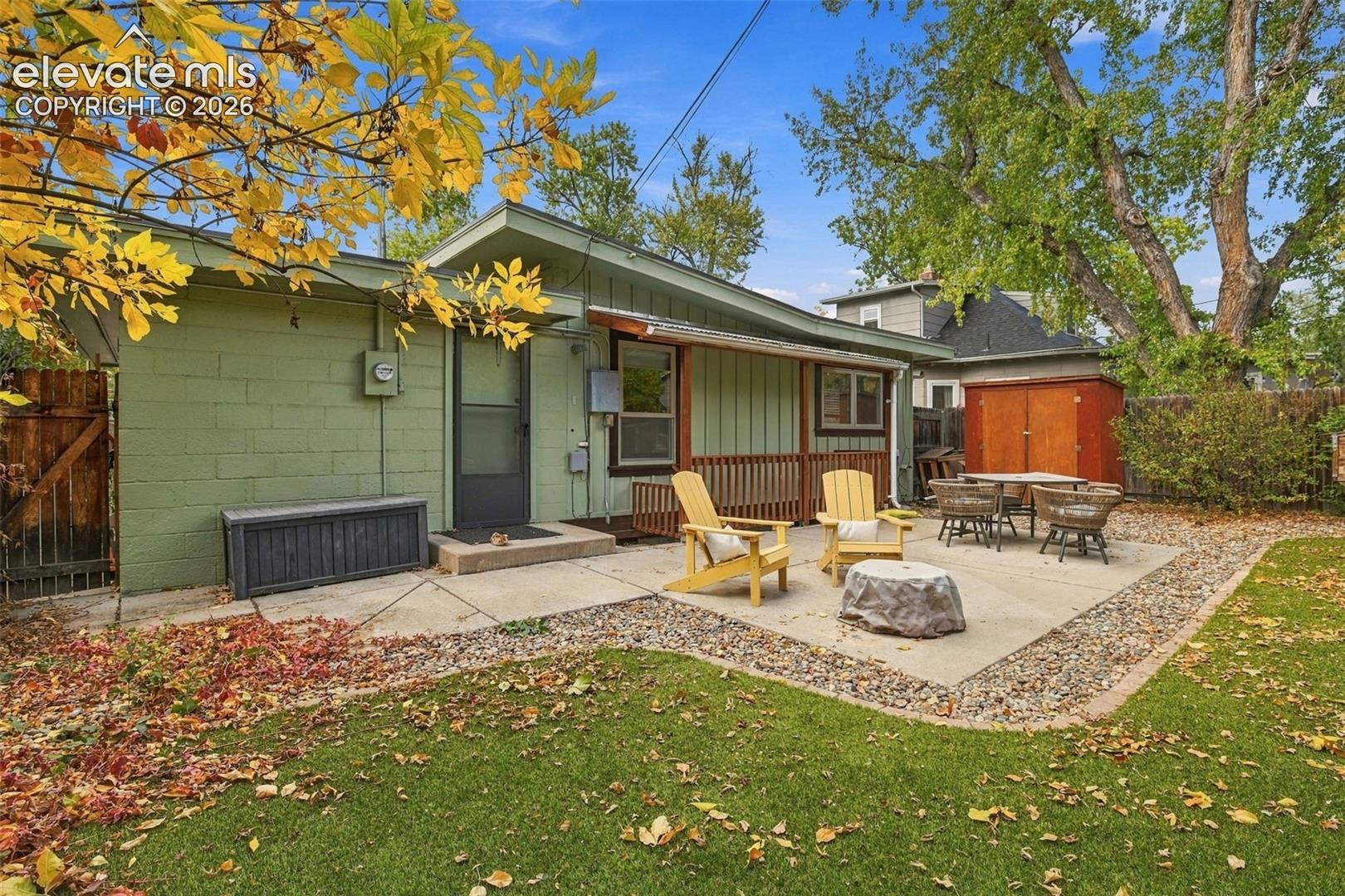 Concrete patio, fenced exterior with vertical siding, attached wood deck, and detached storage shed