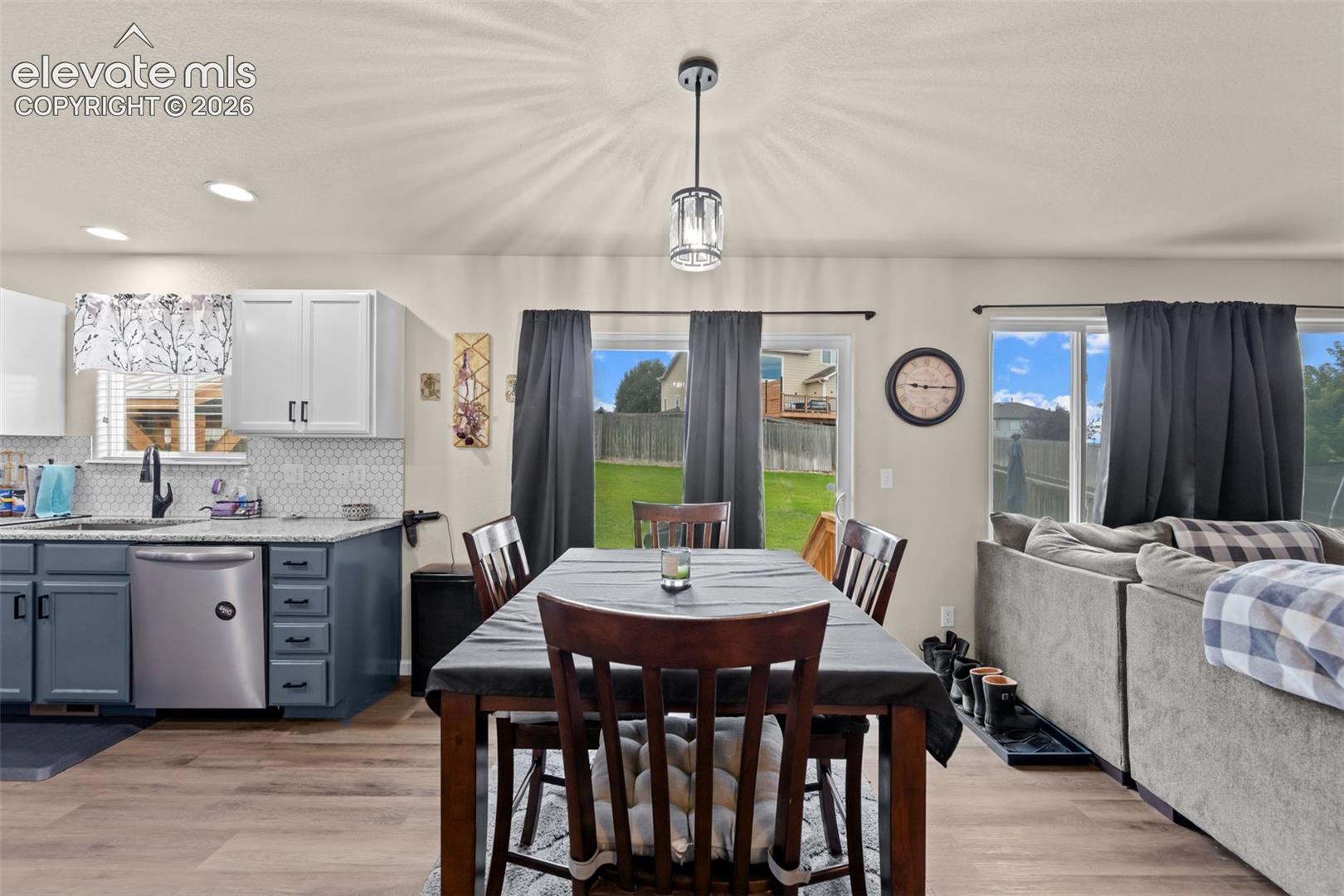 Open-concept living space with wood-finish flooring, recessed lighting, and a contemporary pendant light fixture