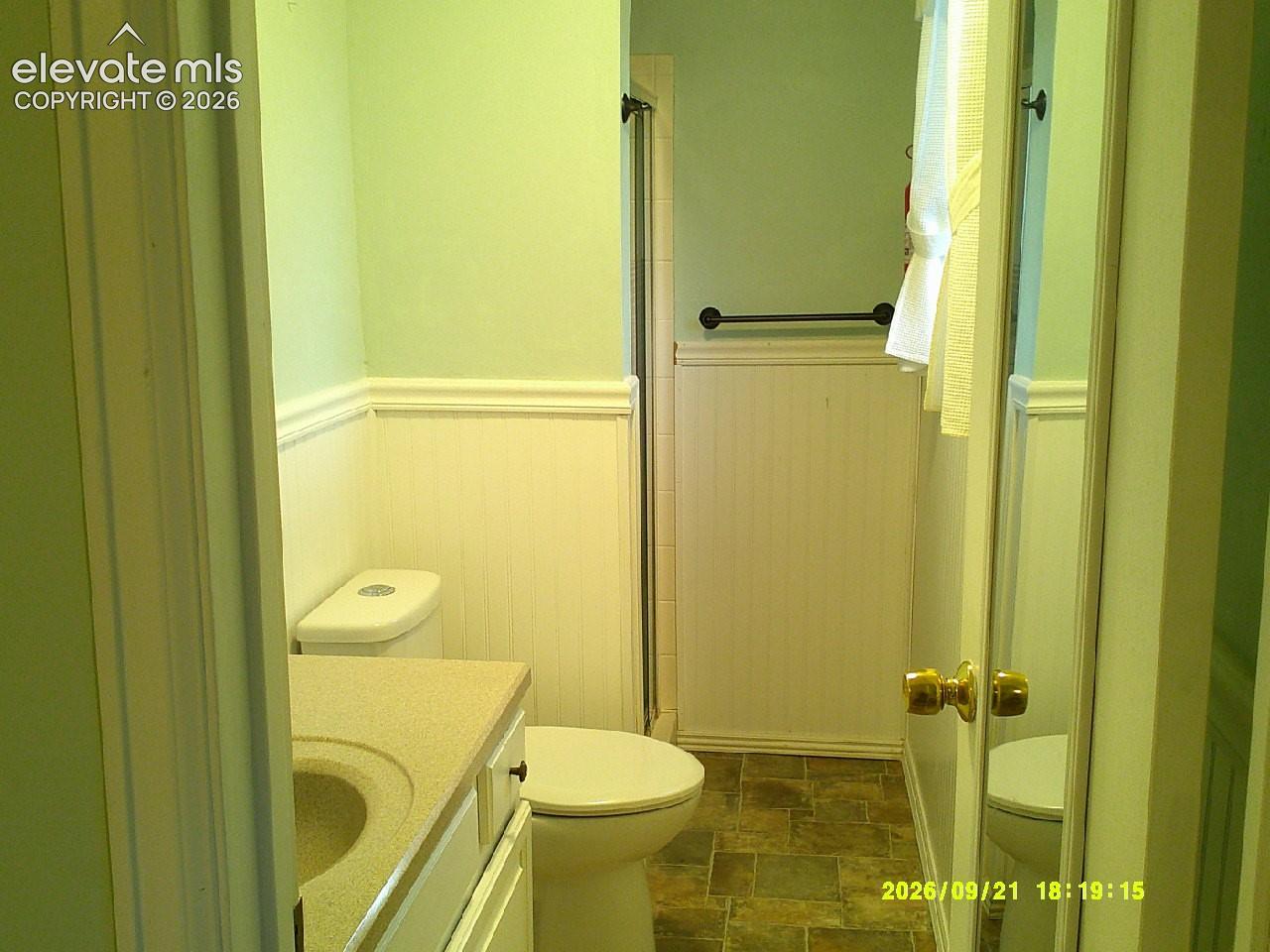 Bathroom featuring wainscoting, a vanity with an integrated sink, and a toilet