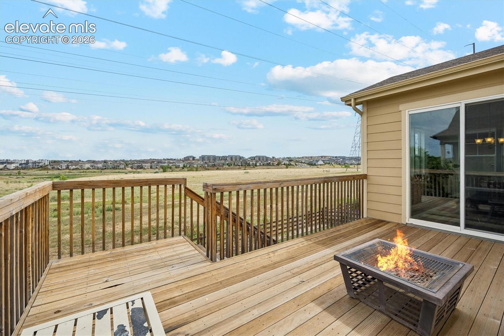Spacious wood deck with a built-in fire pit, offering outdoor living space