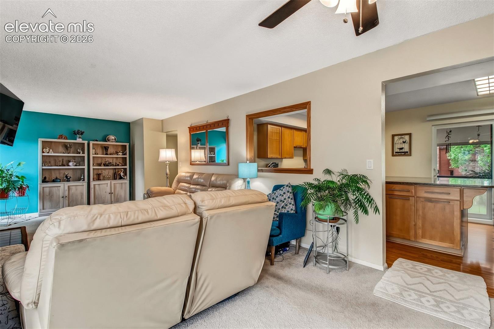 Open floor plan featuring built-in cabinetry, a pass-through wall window, wood-finish cabinetry, and a ceiling fan