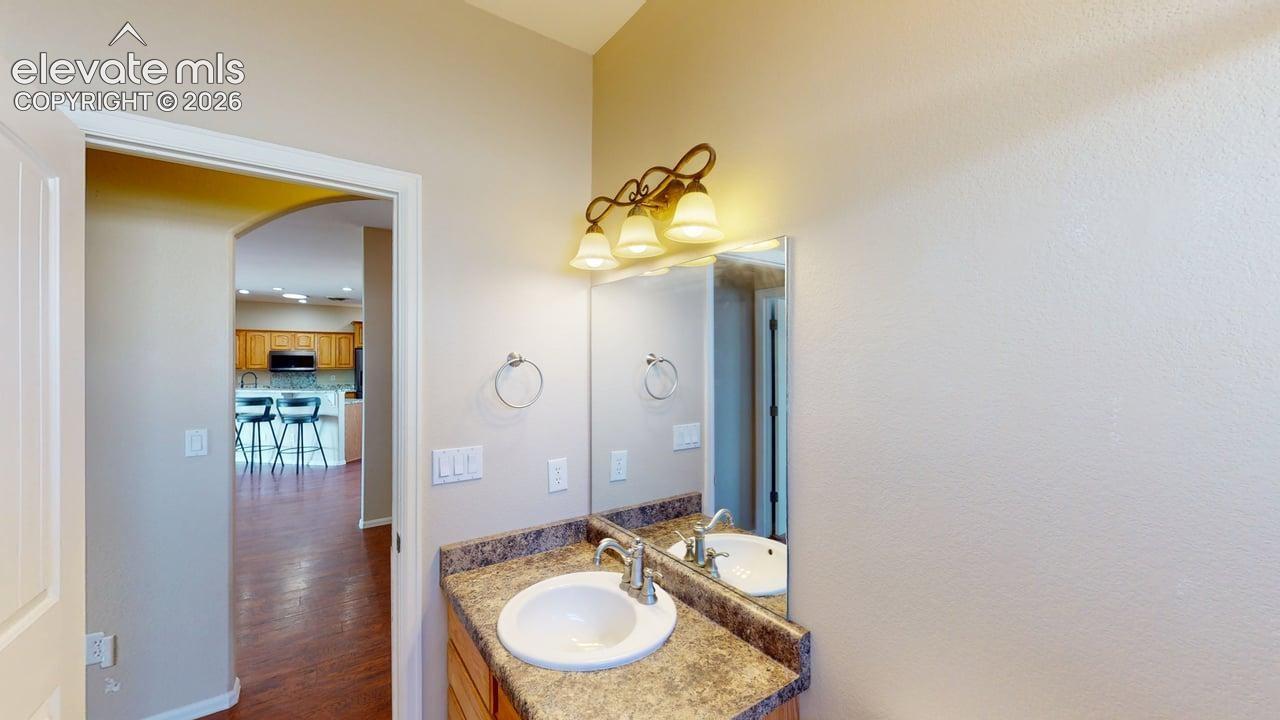 Vanity featuring a single basin sink, decorative wall-mounted light fixture, and a framed mirror