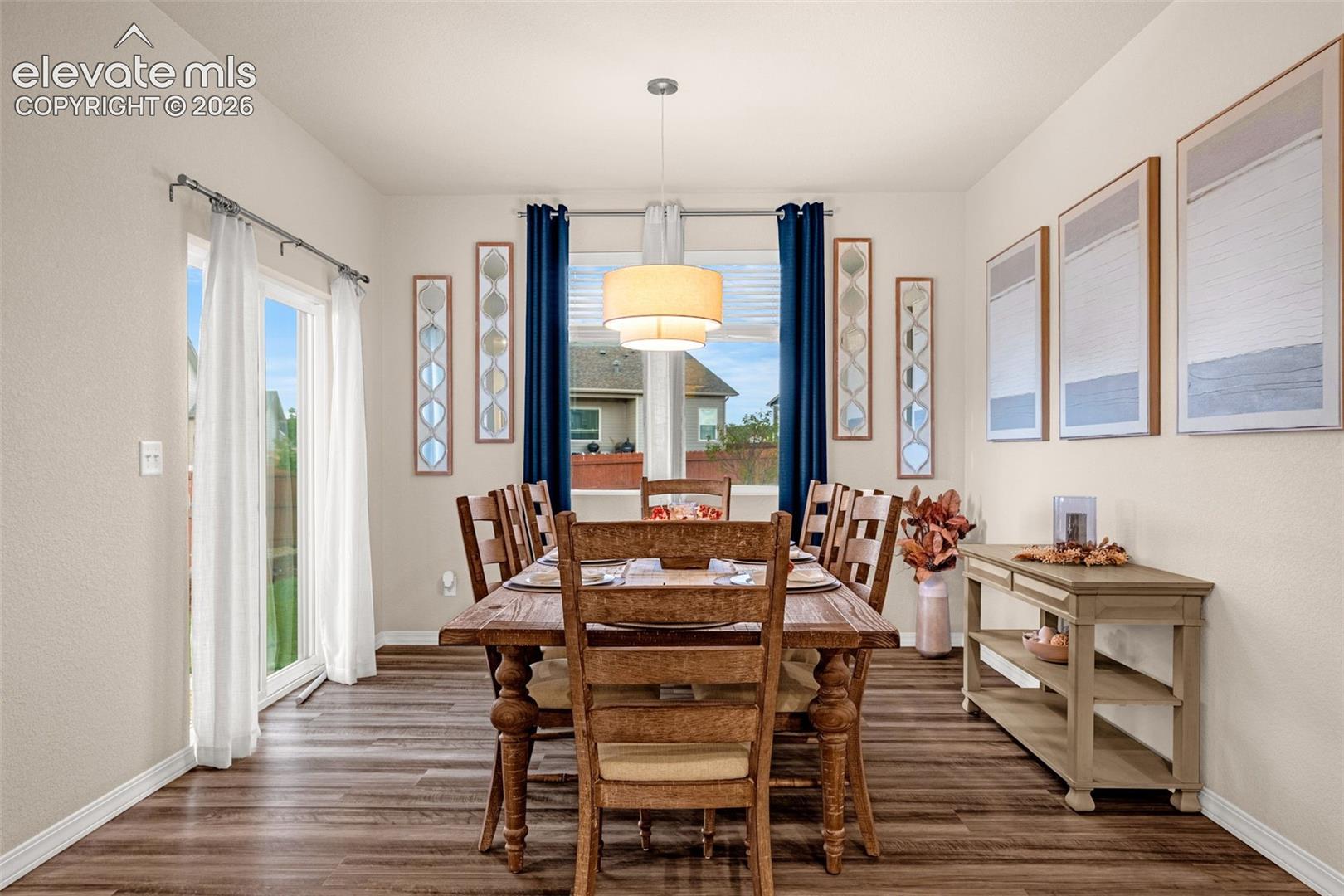 Dining area featuring wood-finish flooring, a contemporary ceiling light fixture, and a sliding glass door