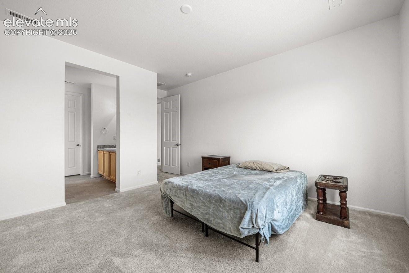 Spacious secondary bedroom with neutral wall finishes, wood-finish flooring throughout, and direct access to hallway with multiple closet doors