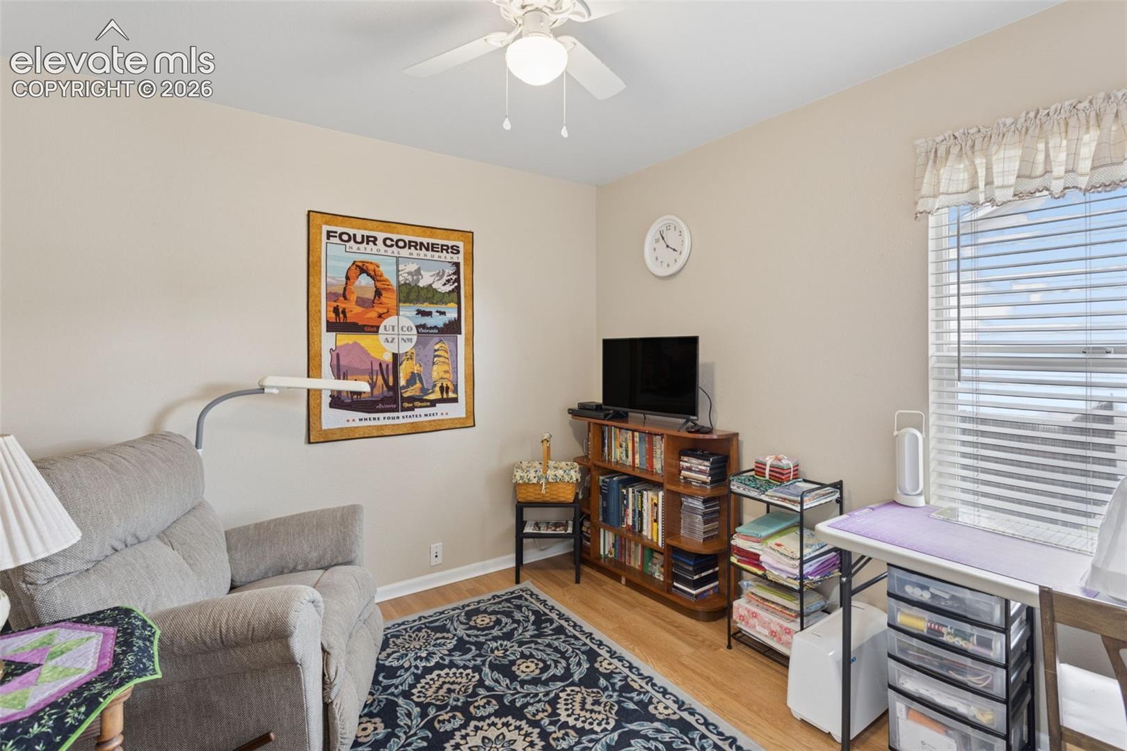 Wood-finish flooring, ceiling fan with light fixture, and a window with blinds