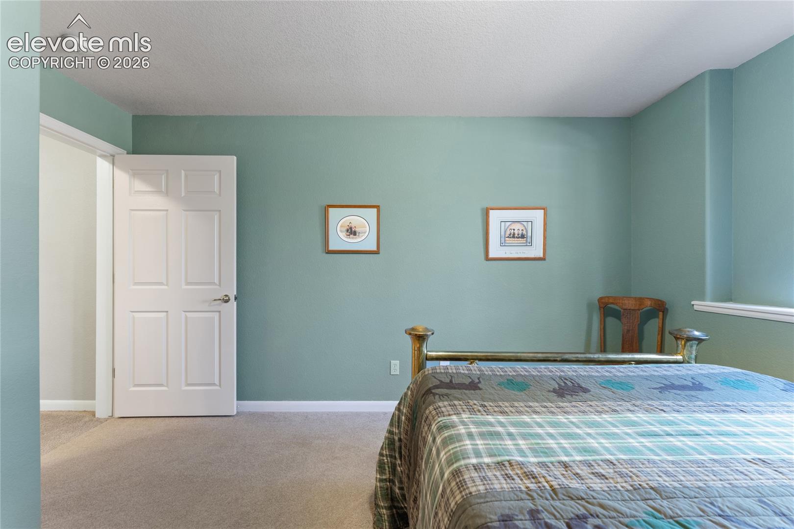 Carpeted interior space featuring light green wall paint, a white six-panel door, and white trim