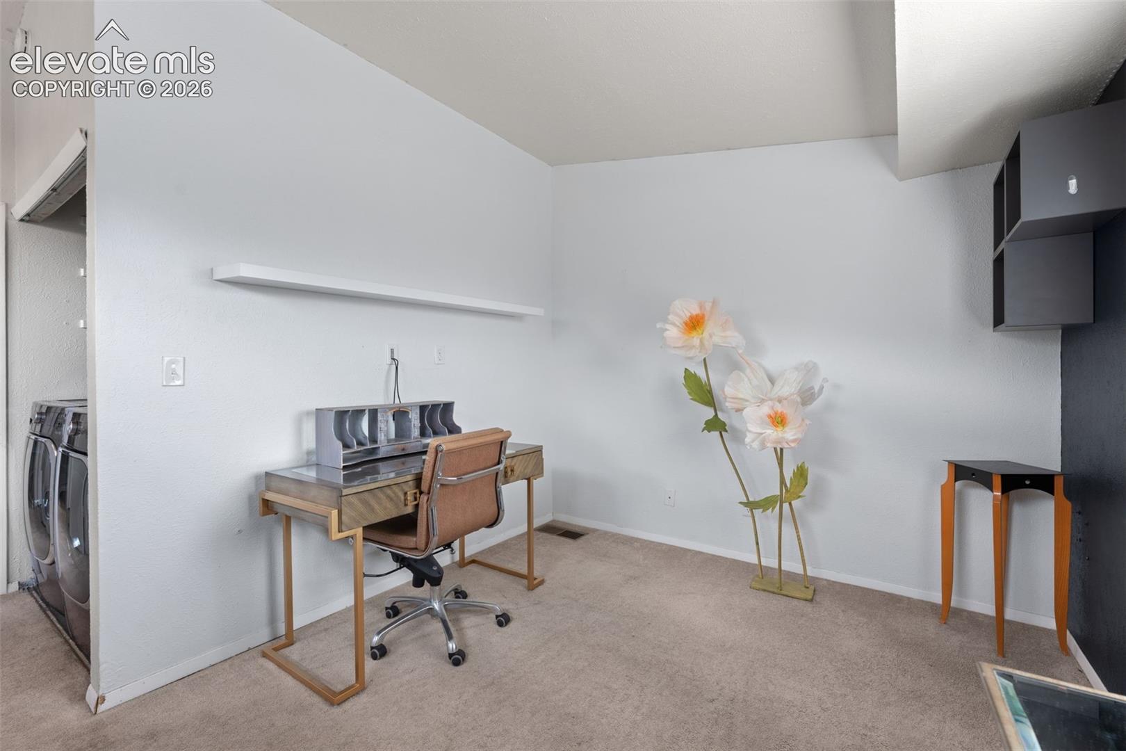 Carpeted room with a wall-mounted shelf and an alcove for appliances