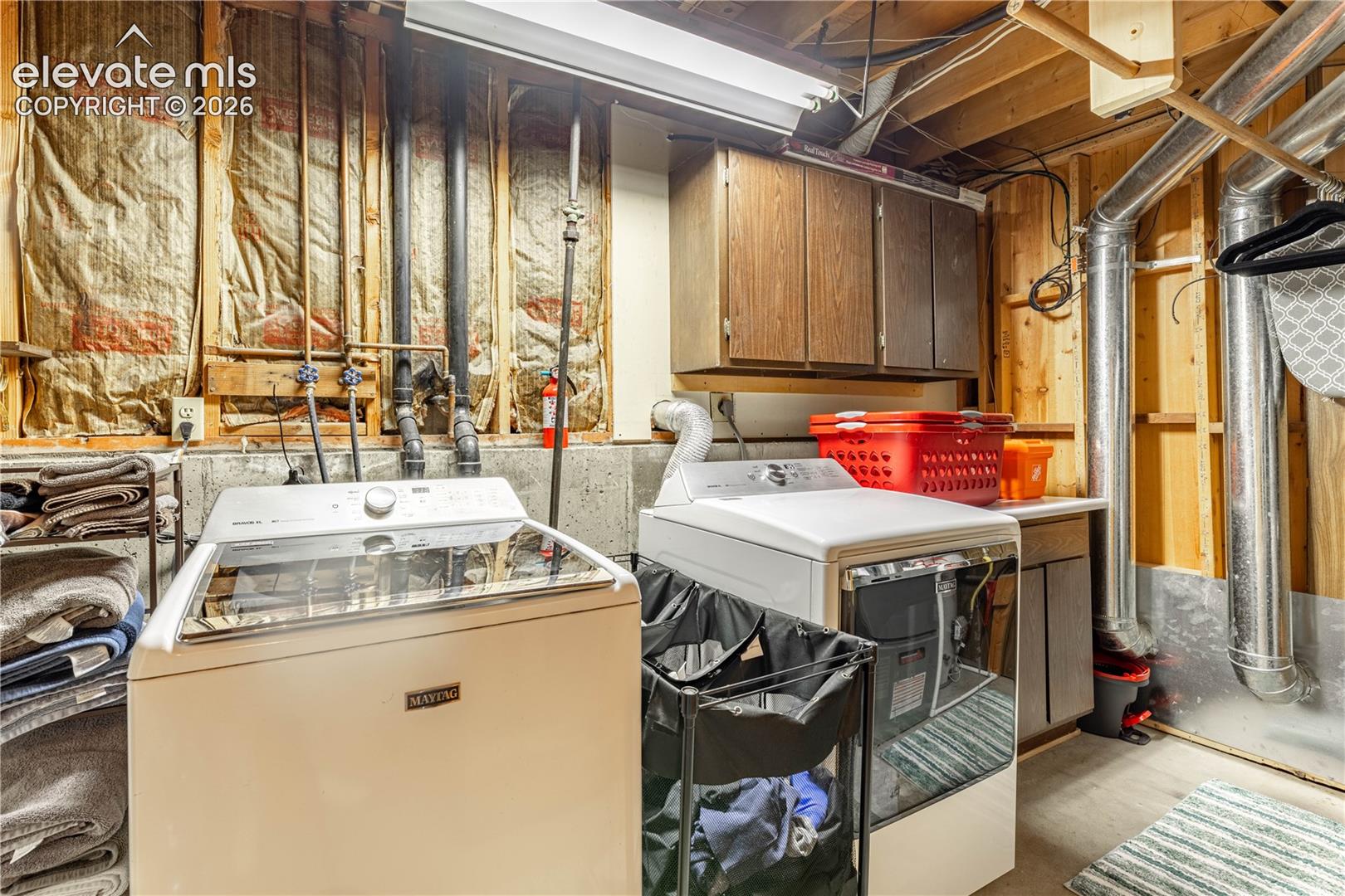 Utility area featuring wall-mounted cabinetry, exposed structural framing, and metal ductwork