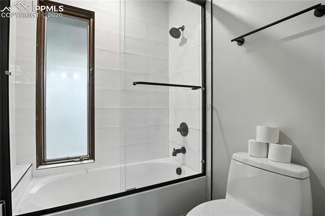 Full bath with bath / shower combo with glass door and toilet