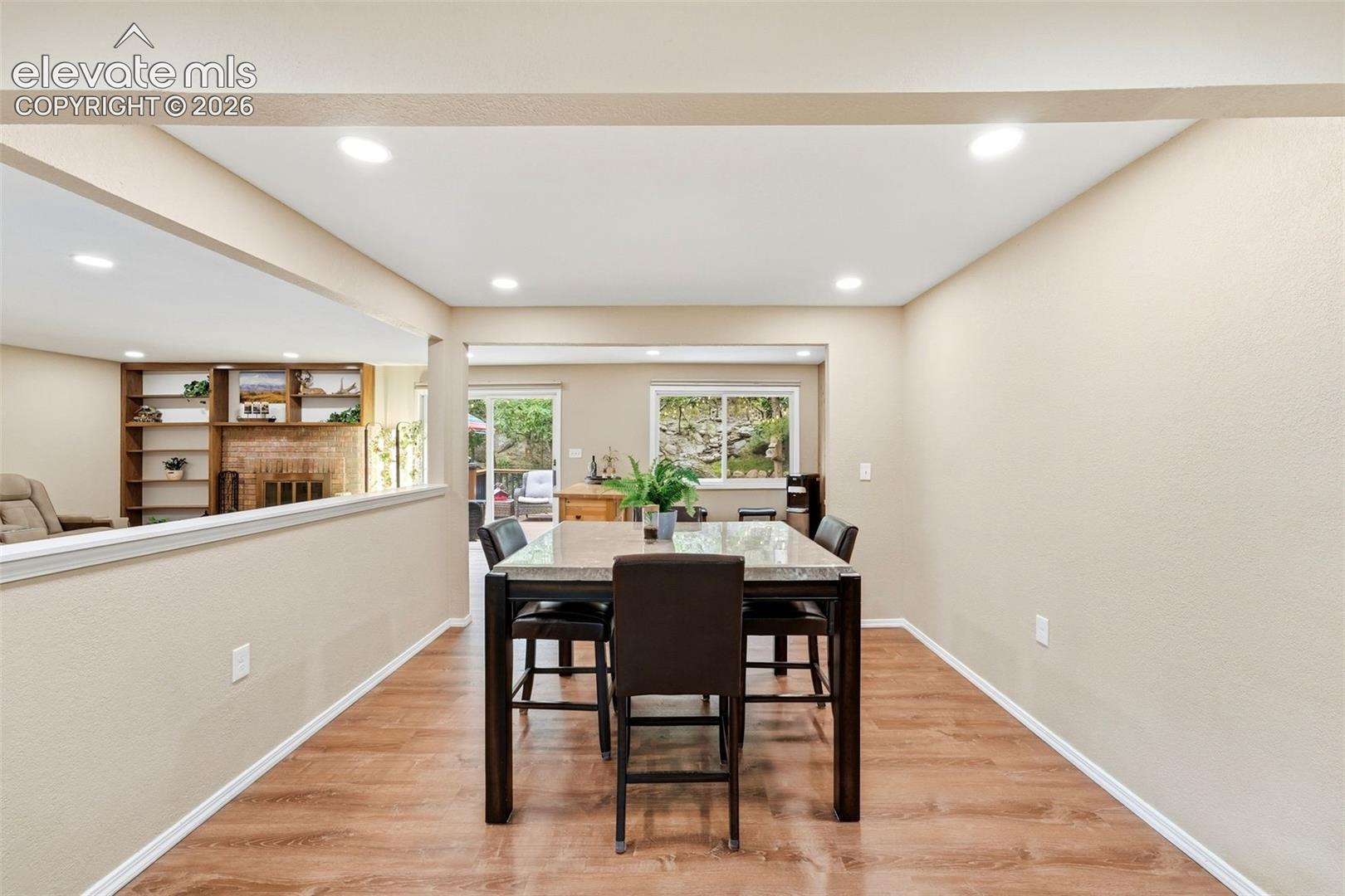 Recessed lighting, wood-finish flooring, half-wall partition, built-in shelving, and a fireplace with a stone surround