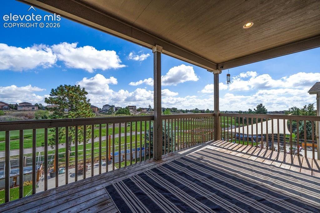 Expansive covered deck featuring wood decking, wood balusters, and a recessed ceiling light