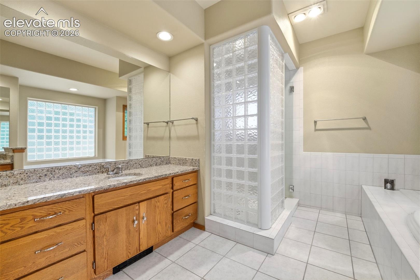 Bathroom featuring a double vanity with wood cabinetry, granite-finish countertop, and integrated sink