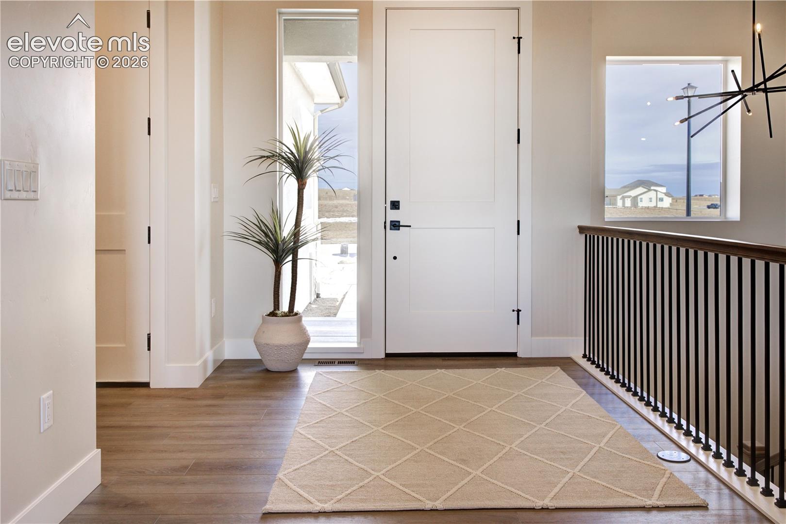 Entryway featuring wood-finish flooring, a solid white door with dark hardware, and a vertical sidelight