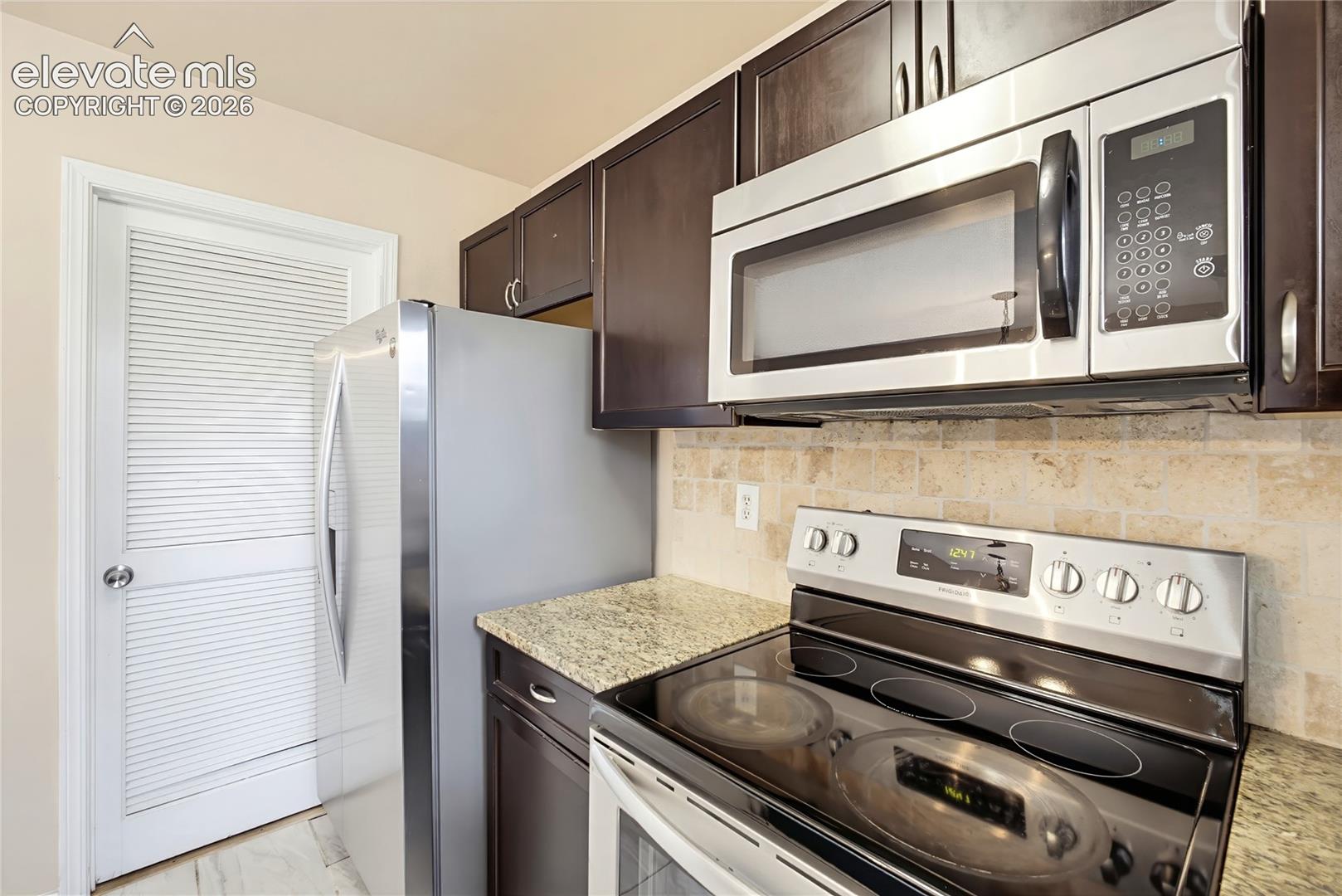Smooth top range oven, built in microwave oven, and side by side stainless steel refrigerator.