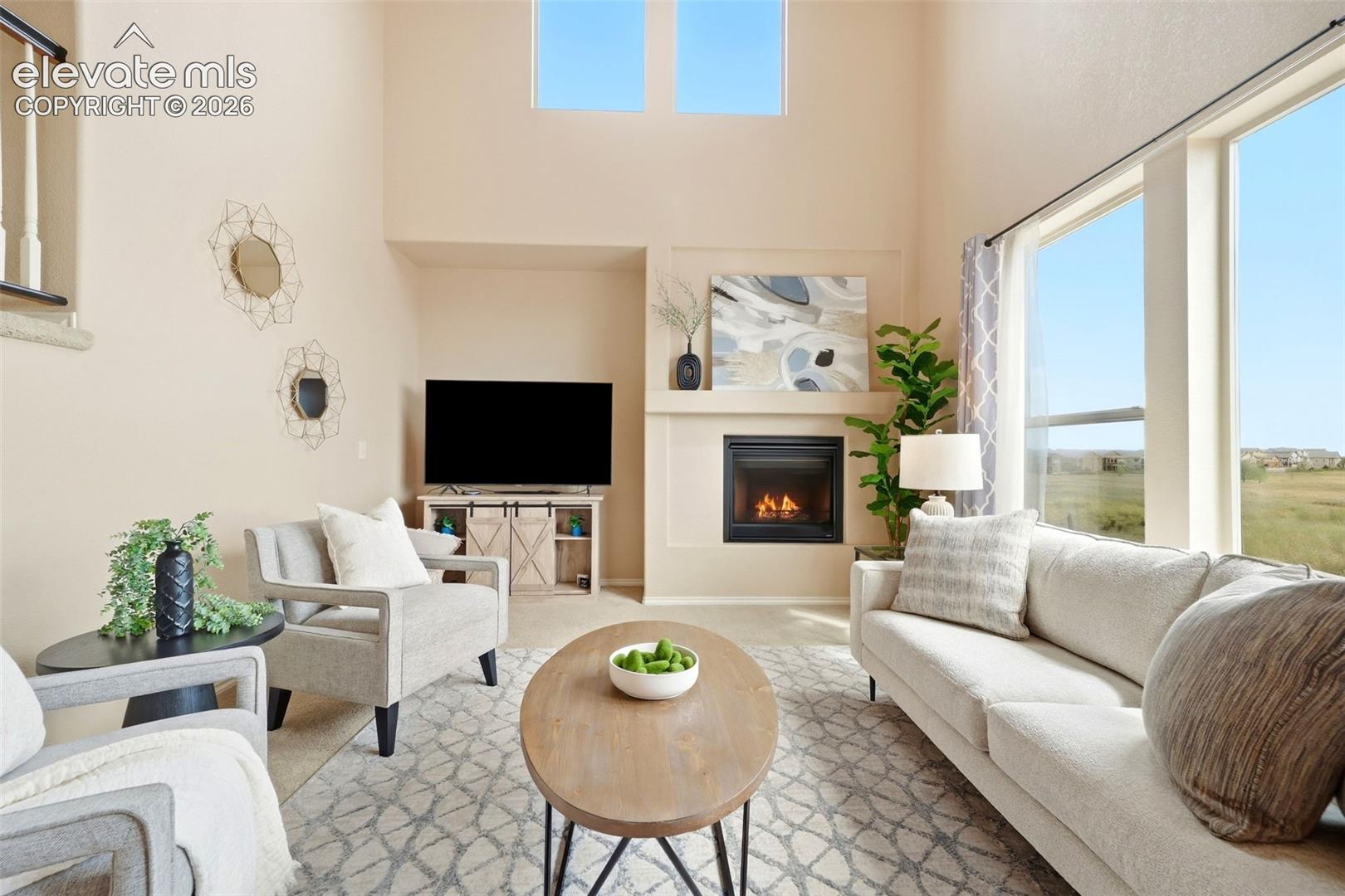 Open living room with high ceilings, tons of natural light, and a gas fireplace