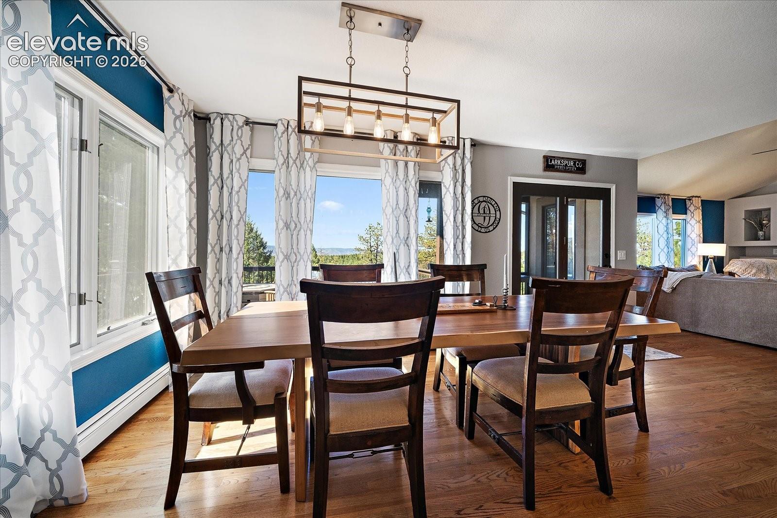 Dining area featuring wood-finish flooring, a geometric metal chandelier, floor-to-ceiling windows, and glass-paneled double doors