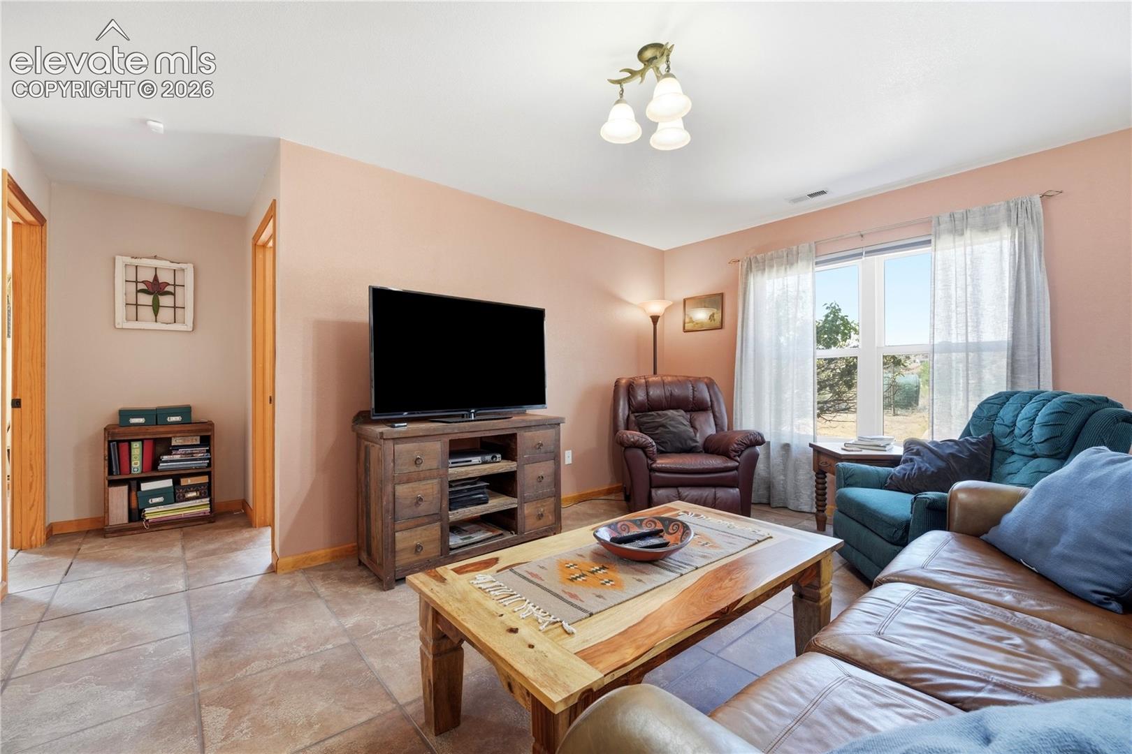 Recessed lighting, tiled flooring, natural wood door frames, and a window with a landscape backdrop