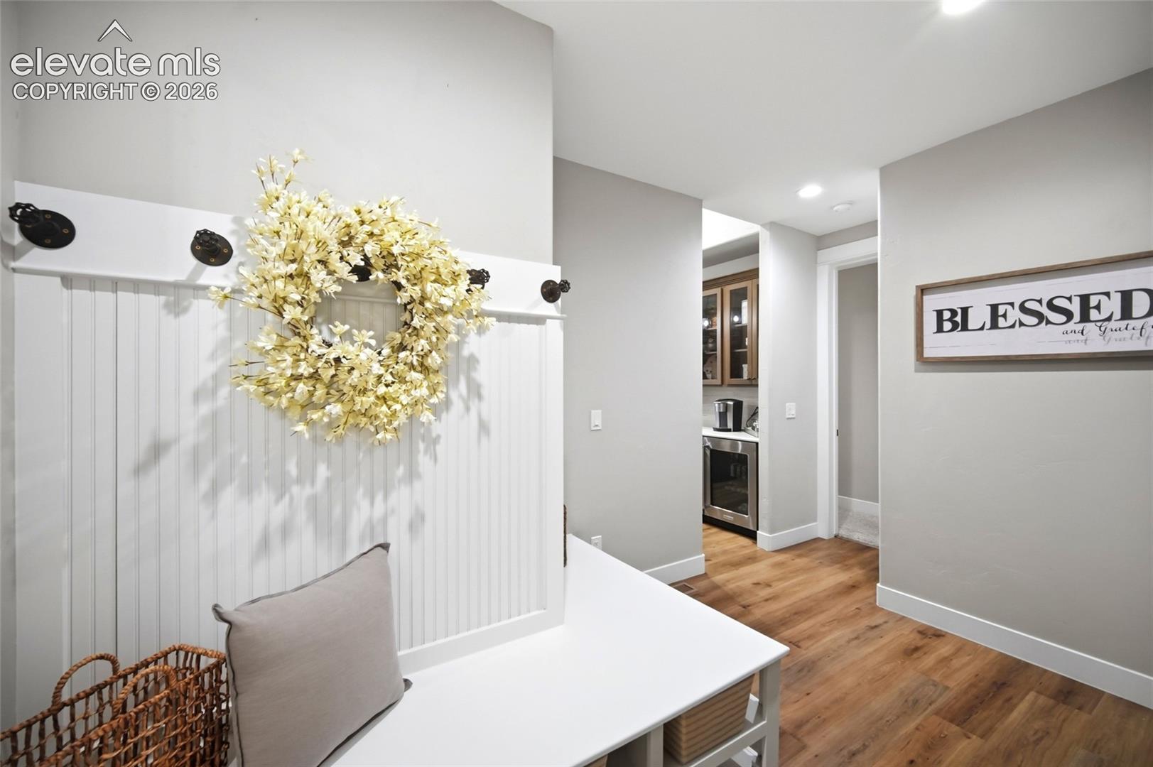 Entryway featuring built-in beadboard cabinetry with iron hardware and wood-finish flooring